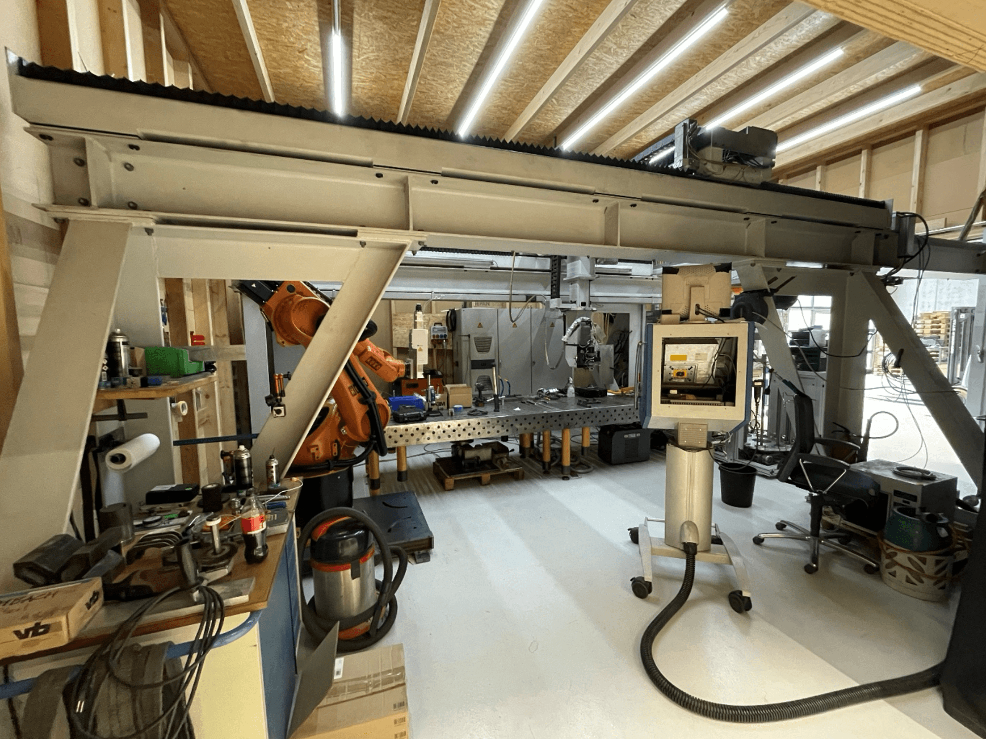 Stiefelmayer Laserhärtenanlage -työkone, etukuva, jossa robottivarsi ja ohjauspaneeli työpajassa.