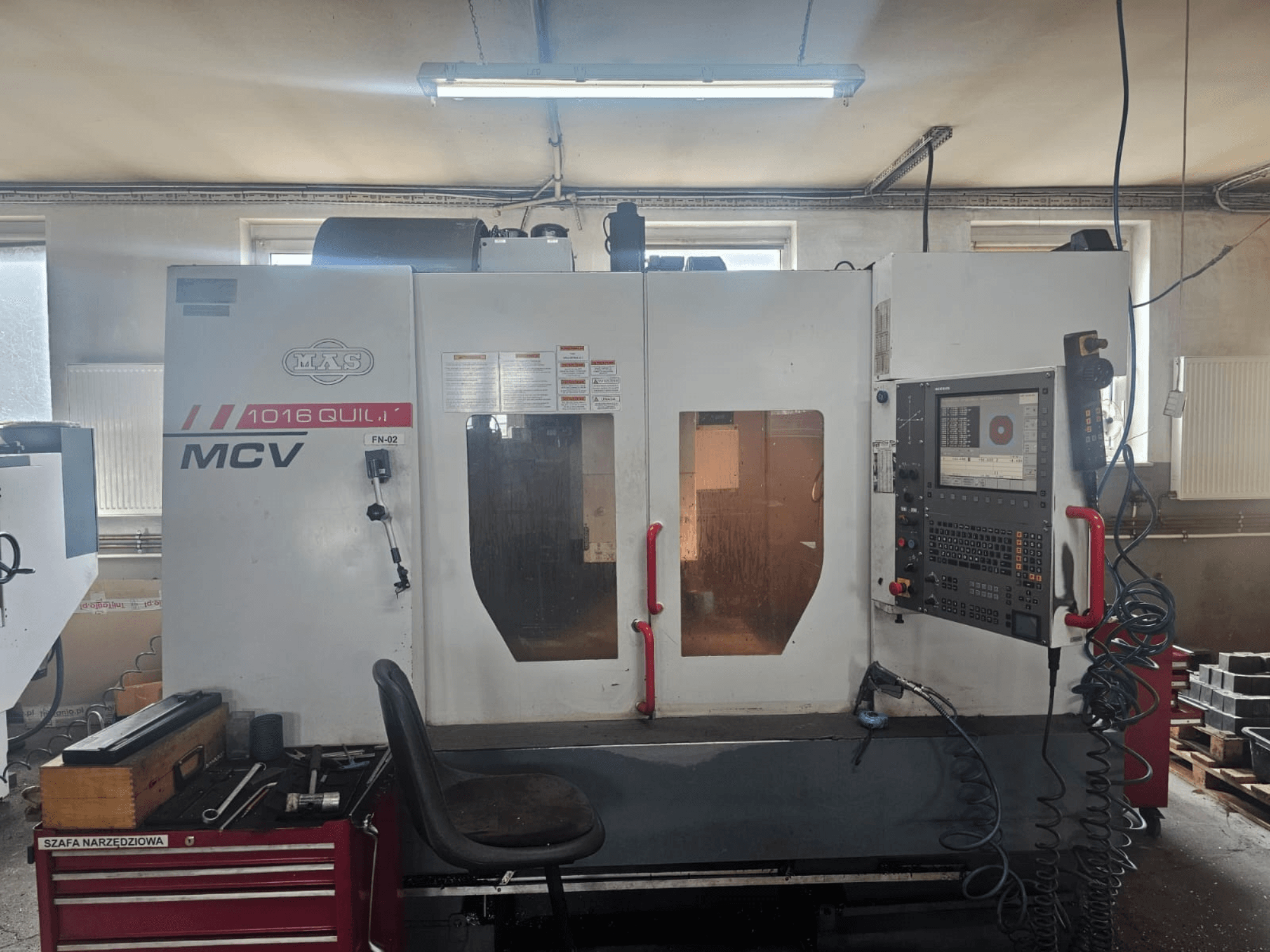 MVS MCV 1016 QUILL CNC-kone, etukuva, jossa ohjauspaneeli, työkalulaatikko ja työtila työkaluineen.