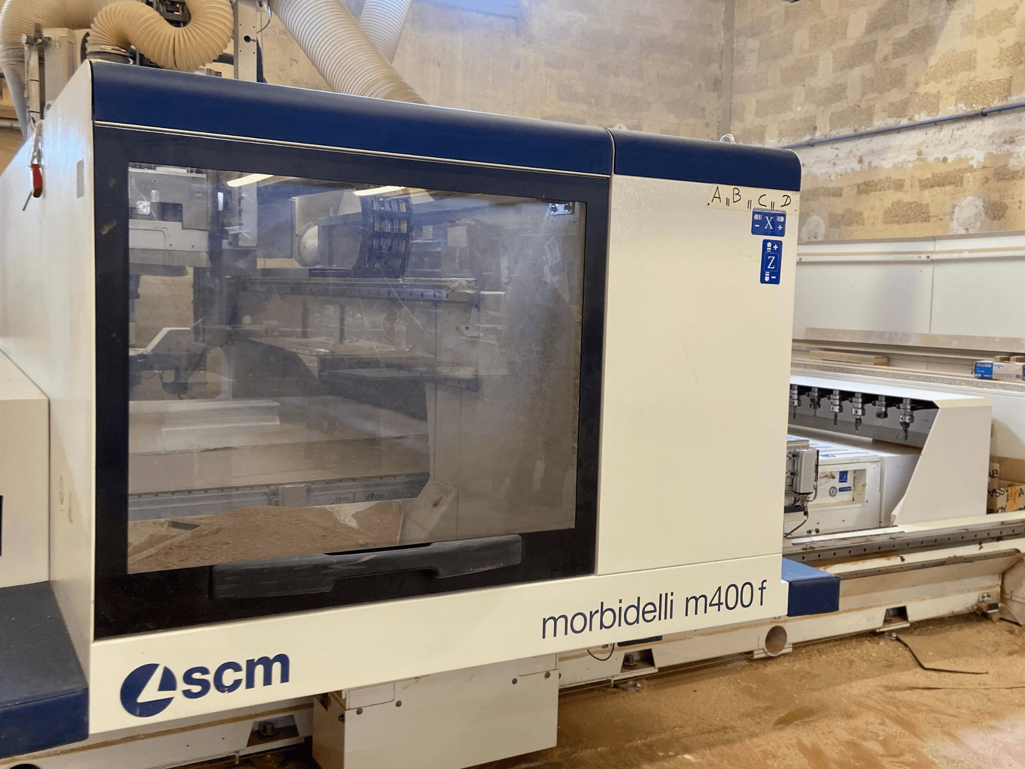 SCM Morbidelli M400F CNC-kone, etukuva, jossa on ohjauspaneeli ja näkyvää sahanpurua lattialla.