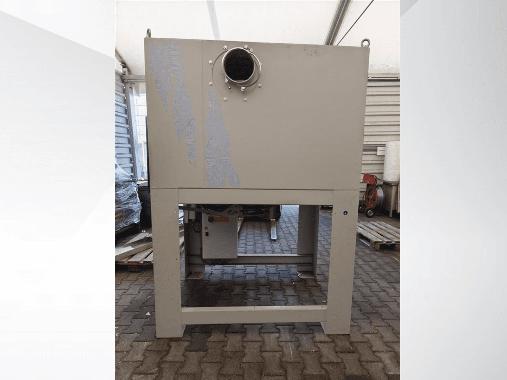 Harmaa teollisuuspölynkerääjä edestä katsottuna, jossa on suuri pyöreä aukko ja joka on asennettu tukevalle jalustalle.