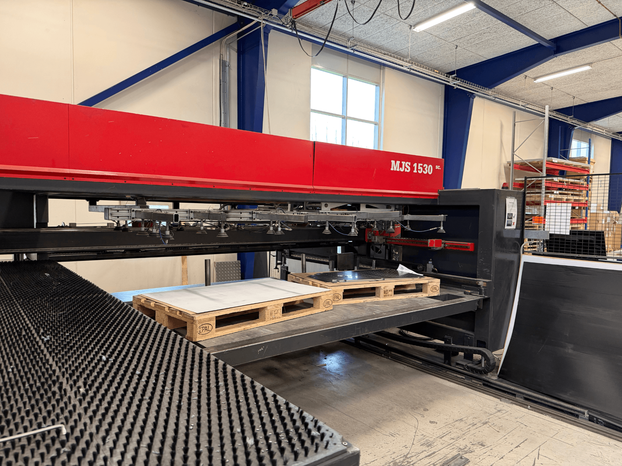 MJS 1530 CNC-kone työpajassa, etukuva, puinen kuormalava, jossa on metallilevy korotetulla alustalla.