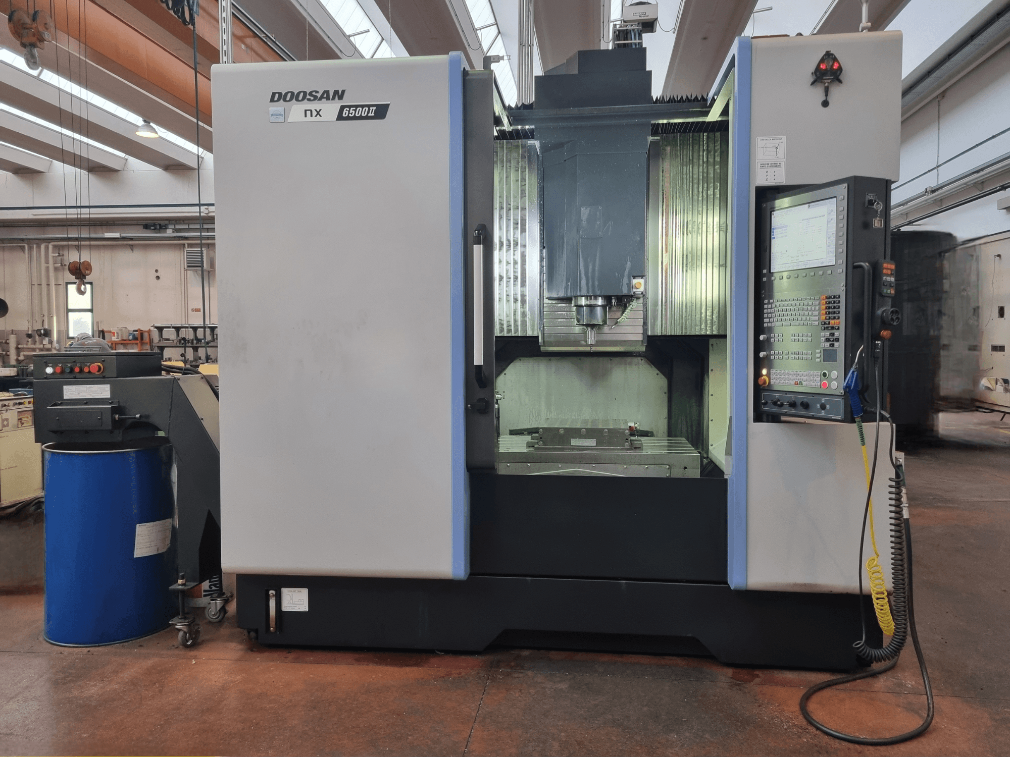 Doosan NX 6500 II CNC-kone, etukuva, jossa ohjauspaneeli ja työstöalue sinisen piipun vieressä.