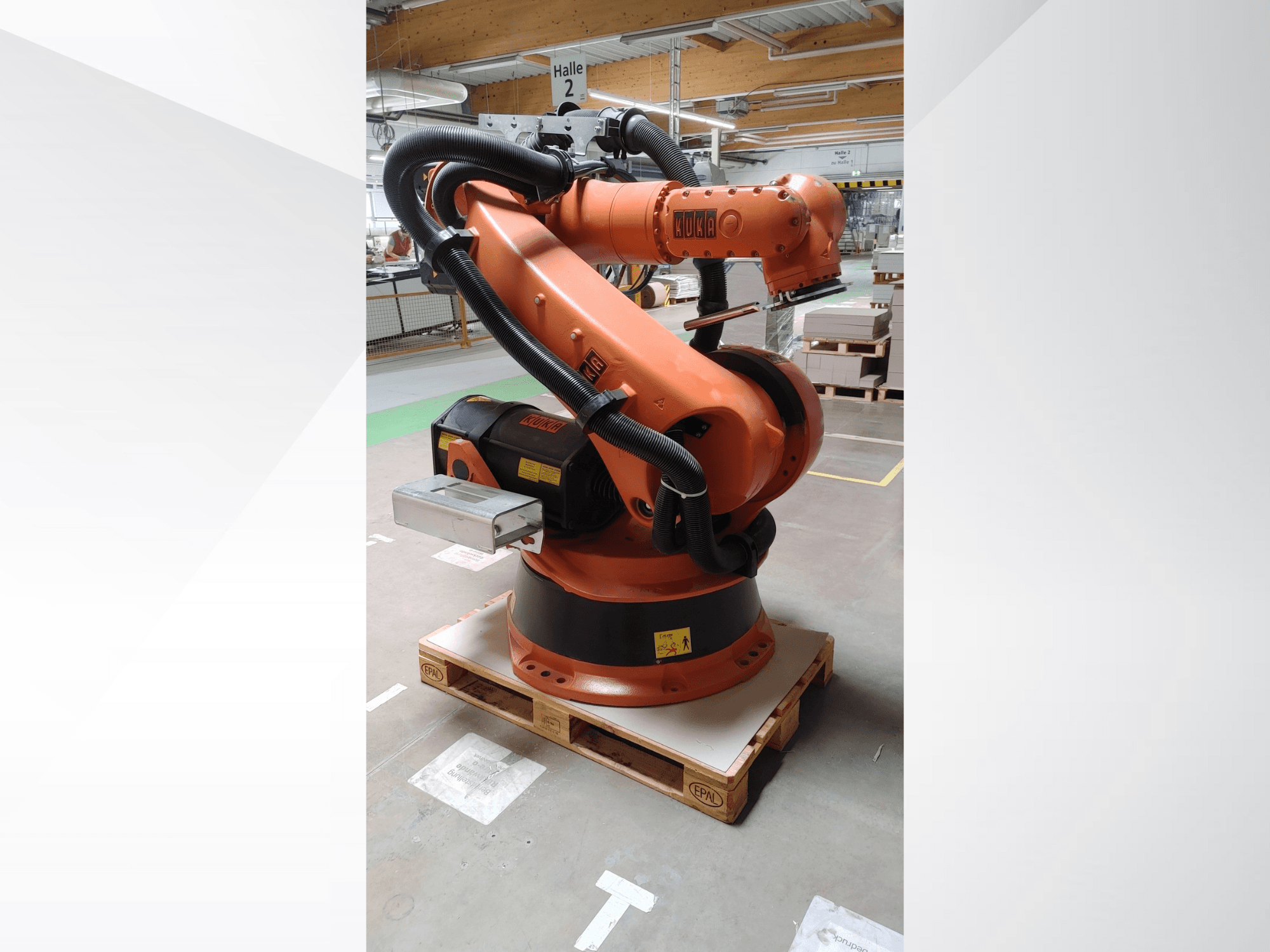 KUKA KR140-3 COMP -robottivarsi, oranssi, etukuva puulavalla, kaareva varsi ja ohjauskotelo.