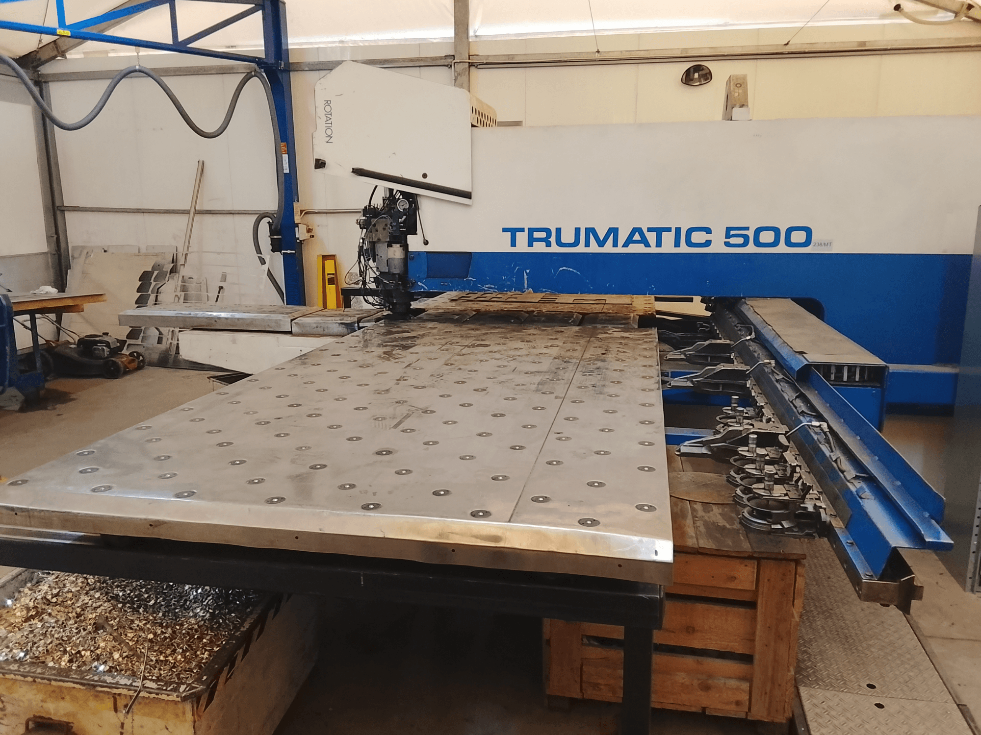 Trumatic 500 CNC-kone, ylhäältä katsottuna, jossa on suuri metallinleikkuupöytä, jonka alle on asennettu työkaluja ja lastuja.