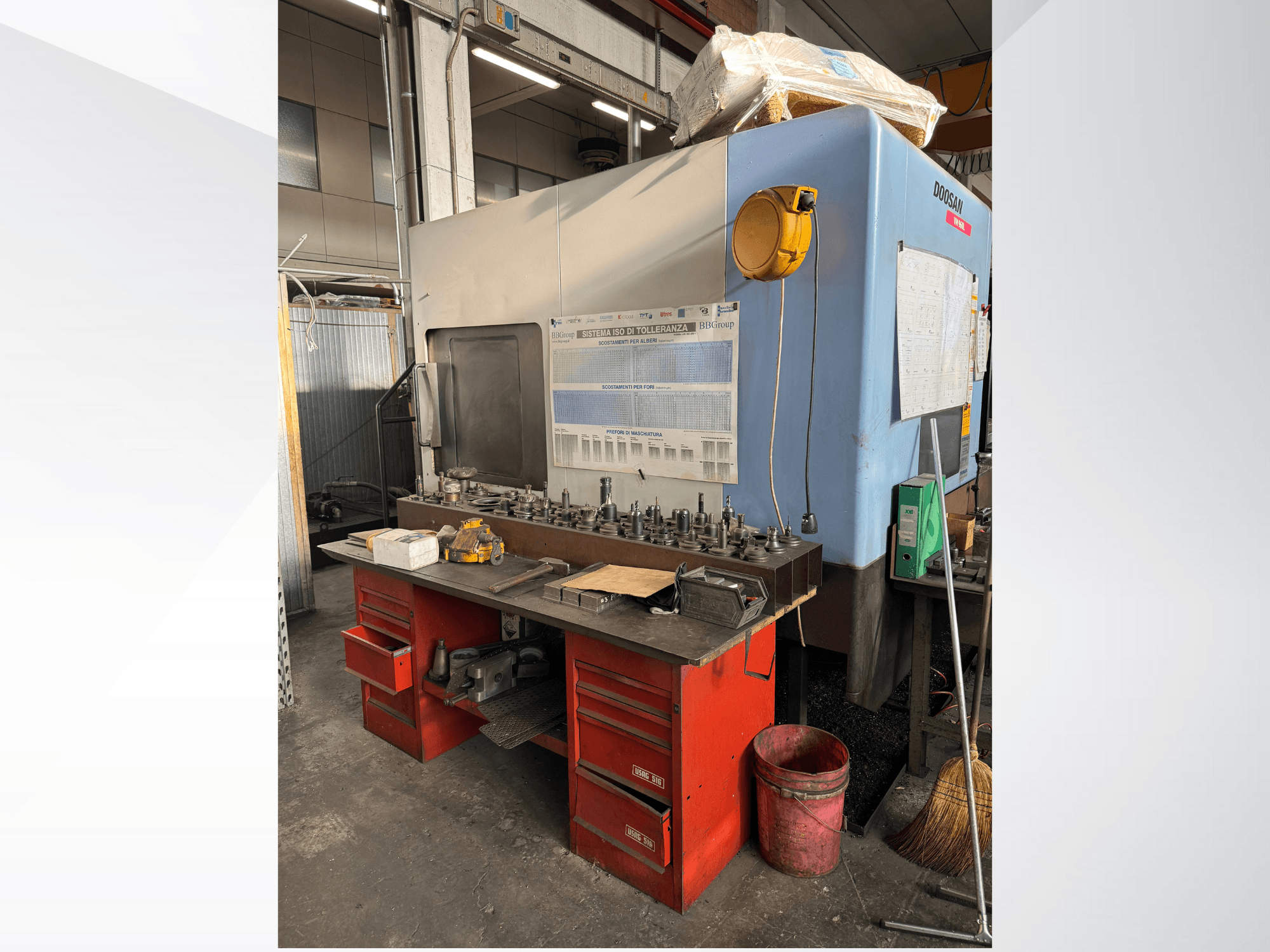 Doosan-työstökeskus, jossa on punainen työpöytä ja varastointi, jossa on työkaluja ja laitteita, edestä katsottuna.