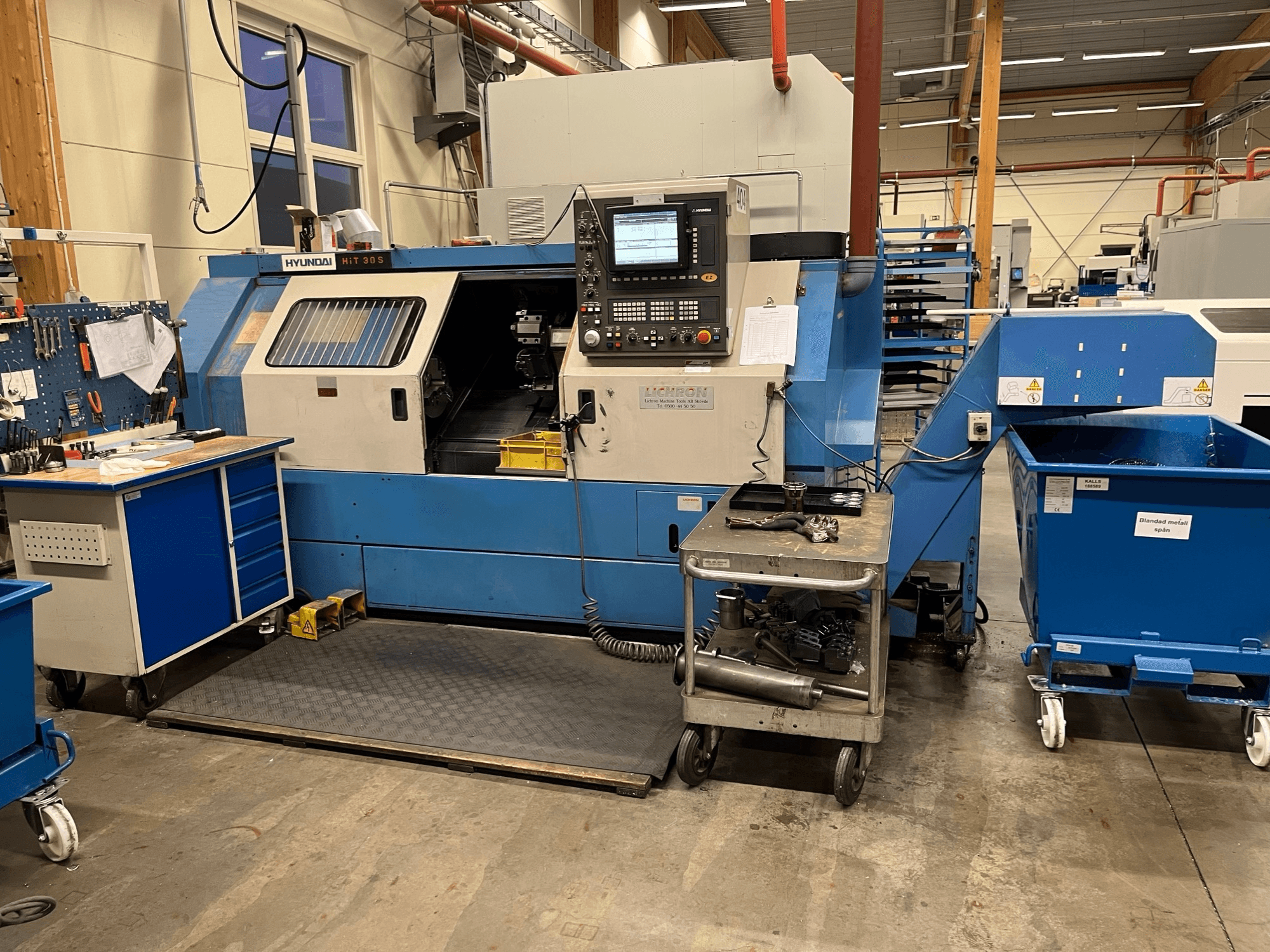 Hyundai HIT 30S vaakasuuntainen sorvauskone, etukuva, ohjauspaneeli ja työkalut läheisellä kärryllä korjaamolla.