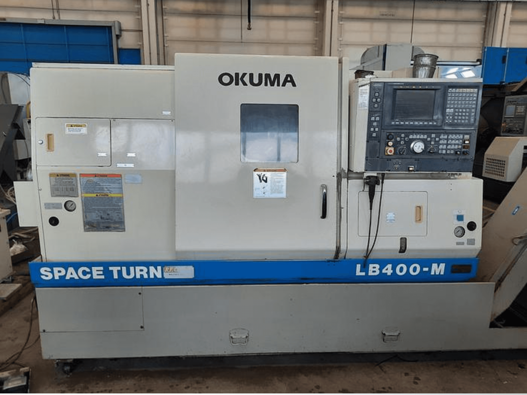 Okuma LB400-M CNC-sorvi, etukuva, jossa ohjauspaneeli, varoitustarrat ja sininen "SPACE TURN" -merkki näkyvissä.
