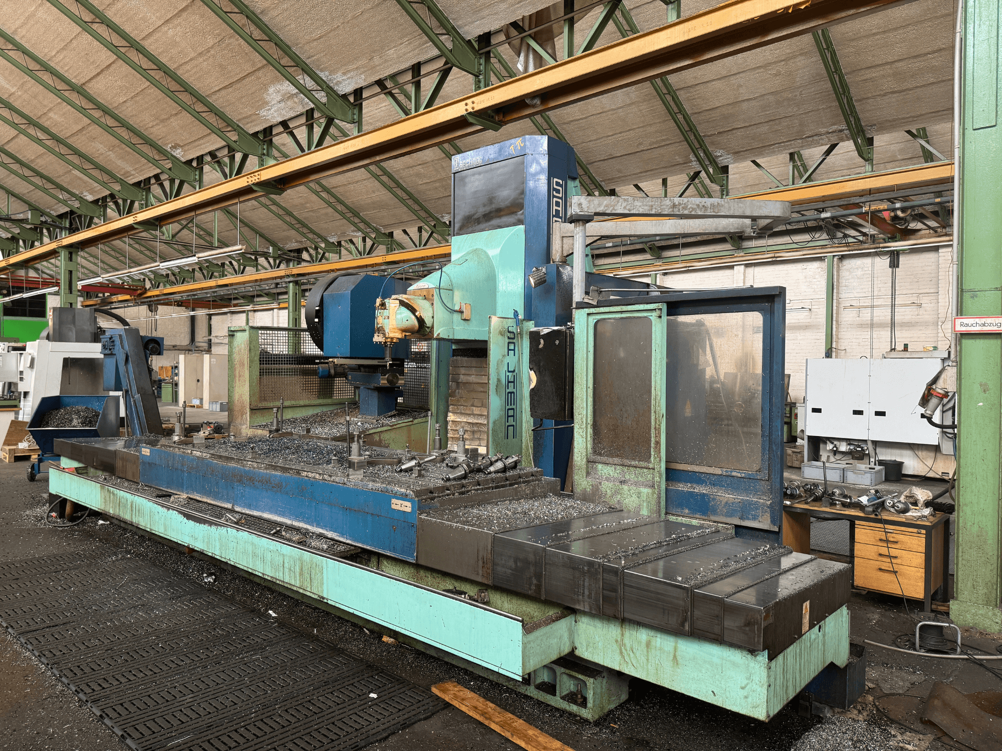 Salvador-jyrsinkone tehdasasennossa, etukuva, sininen ja vihreä värimaailma, jossa näkyy metallilastuja sängyllä.