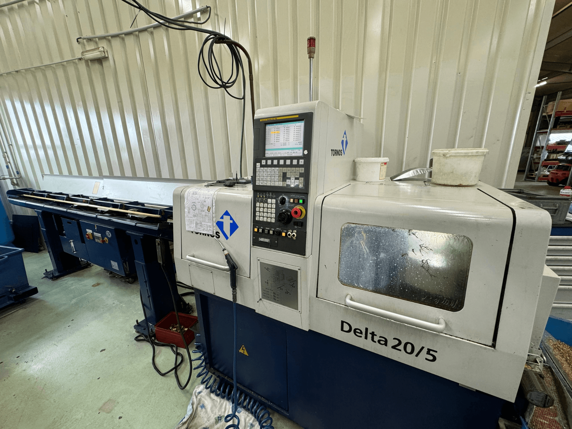 Torino Delta 20/5 CNC-kone, etukuva, ohjauspaneeli ja työtila. Sisältää syövytettyä lasia ja näkyvät johdotukset.
