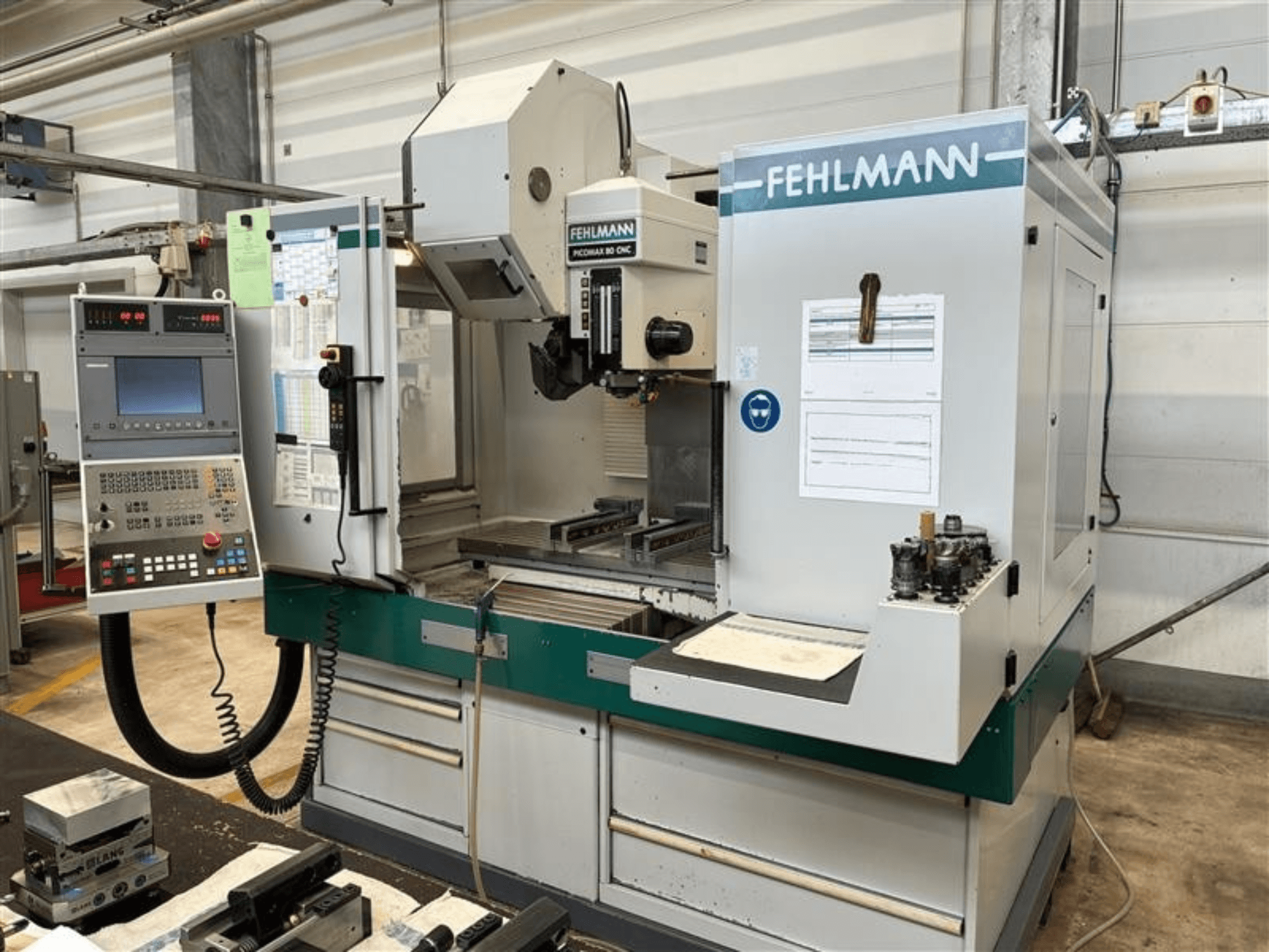 FEHLMANN PICOMAX 80 CNC-W 2/3 -pystykoneistuskeskus edestä katsottuna; kuvassa näkyvät ohjauspaneeli ja työstöalue.