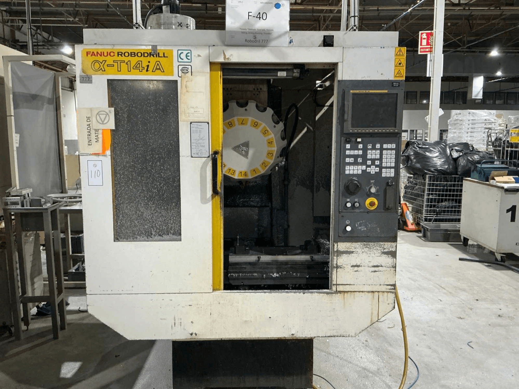 FANUC ROBODRILL α-T14iB -pystytyöstökeskus, etukuva, jossa näkyy ohjauspaneeli ja työkalukaruselli.