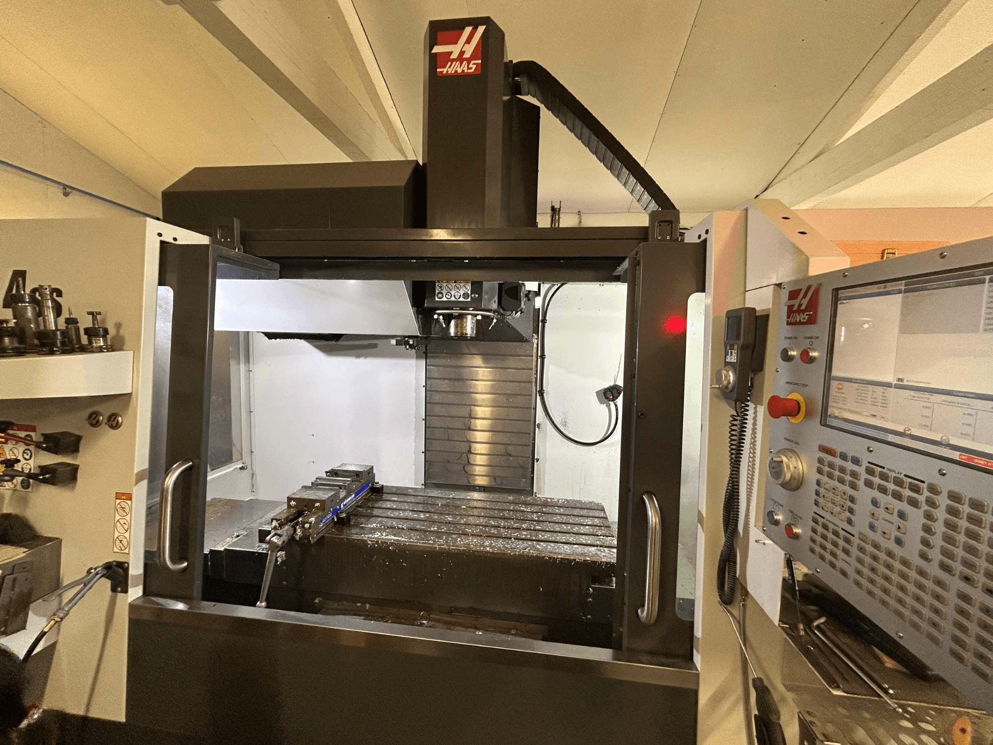 HAAS VF-4SS -pystytyöstökeskus, etukuva, jossa näkyy ohjauspaneeli, työkalunpidin ja työalue, jossa on metallilastuja.