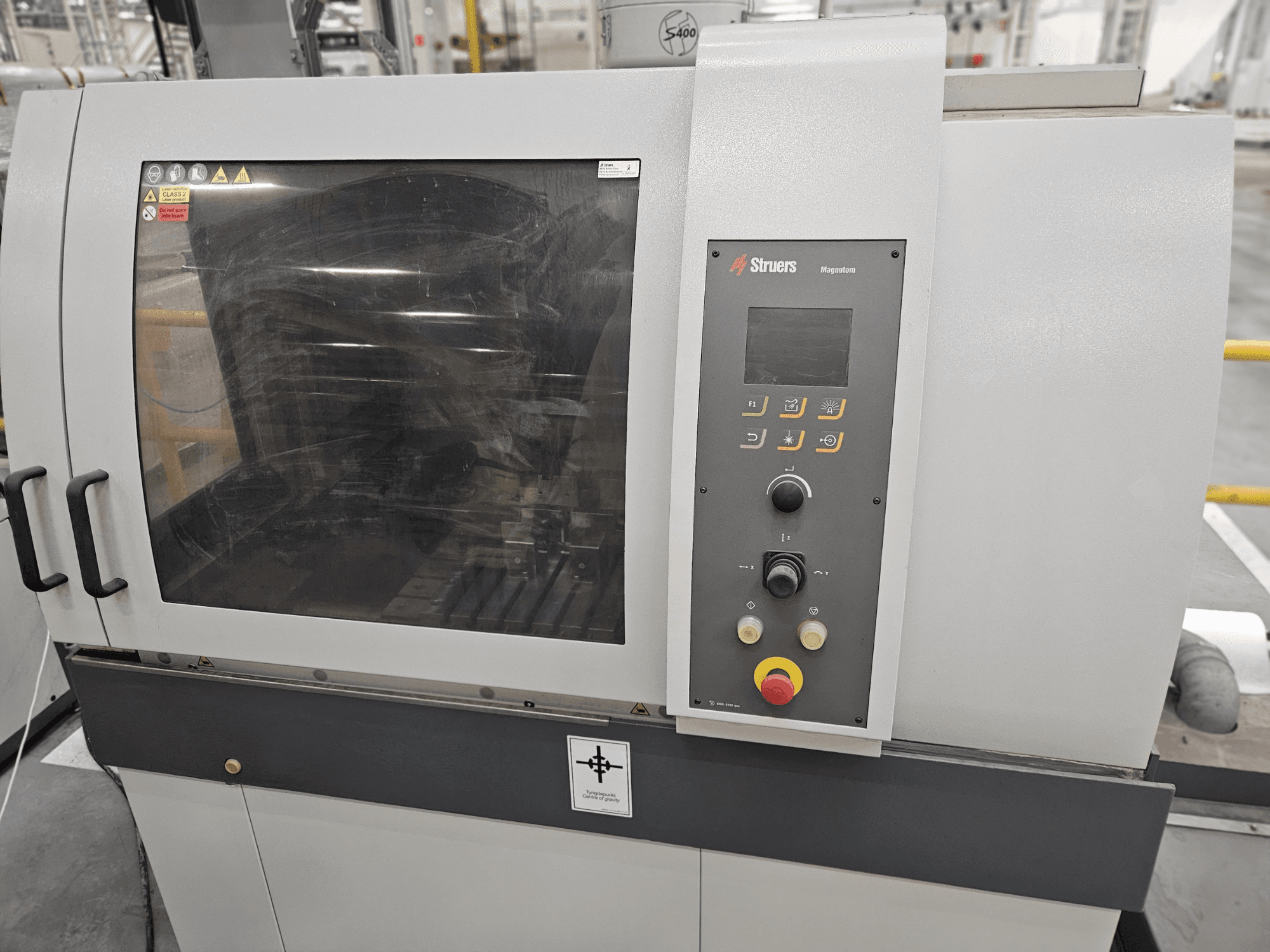 Struers Magpentor -koneen etukuva, jossa on ohjauspaneeli, painikkeet ja suuri näyttöikkuna. Tekniset merkinnät näkyvissä.