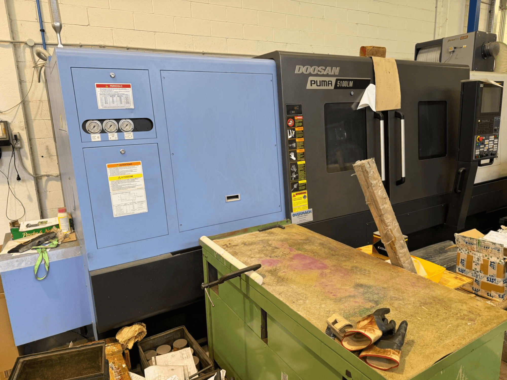 Doosan Puma 5100LM CNC-kone ja ohjauspaneeli, sivukuva. Mittarit ja varoitustarrat näkyvissä sinisessä ohjausyksikössä.