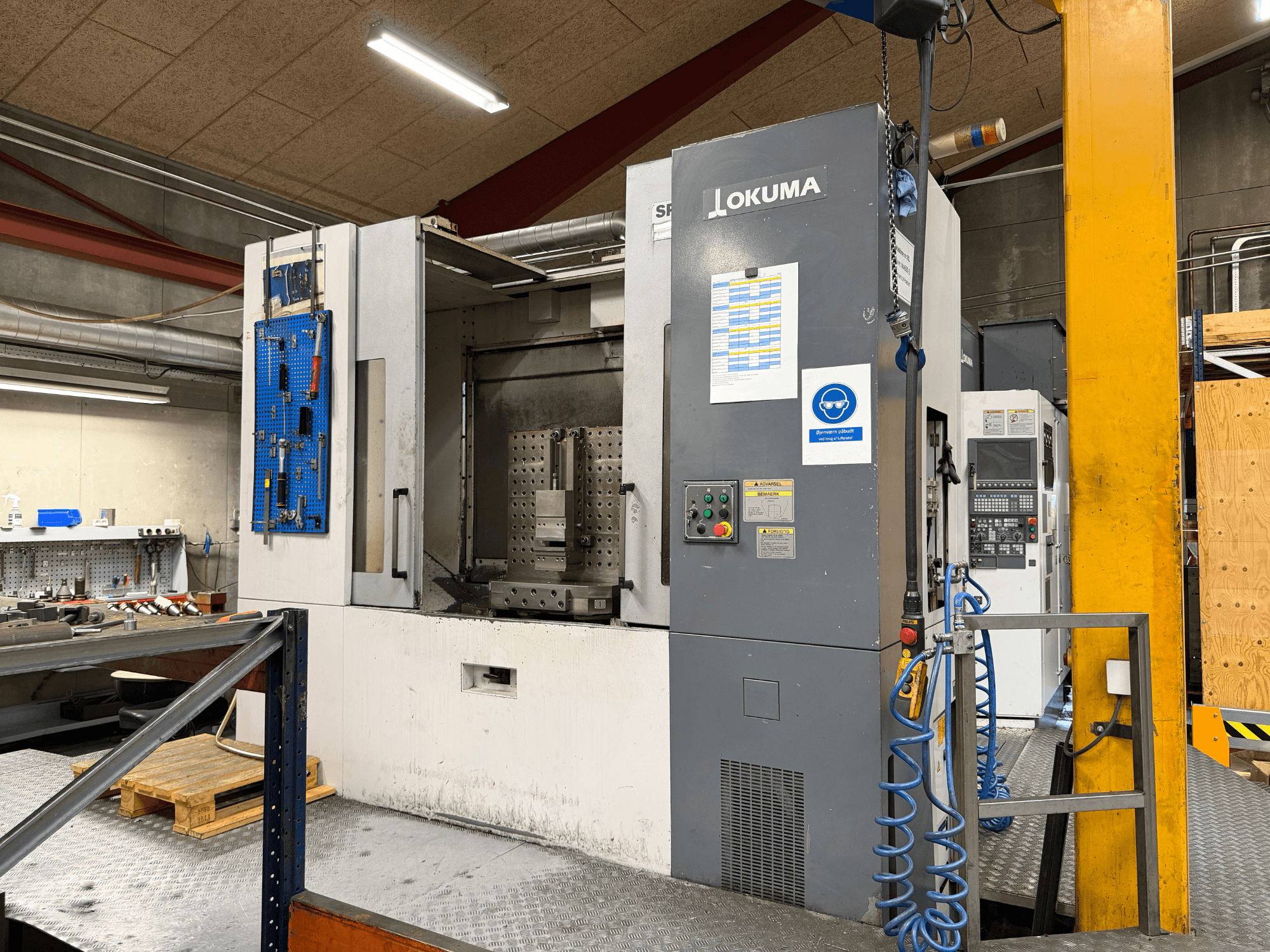 Okuma MA-600HB -vaakakoneistuskeskus työpajassa; etunäkymä, jossa näkyvät ohjauspaneeli ja työstöalue.