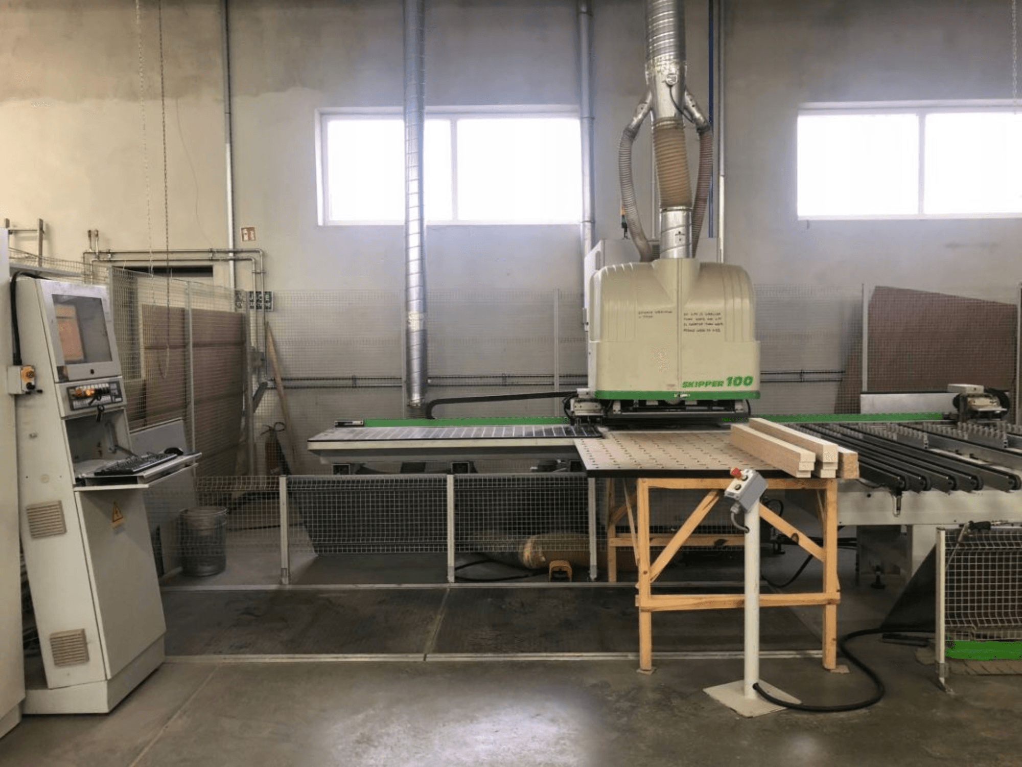 BIESSE SKIPPER 100 CNC-työstökeskus työpajassa; etunäkymässä näkyy kone ohjauspaneelineen sekä pöydällä oleva puu.