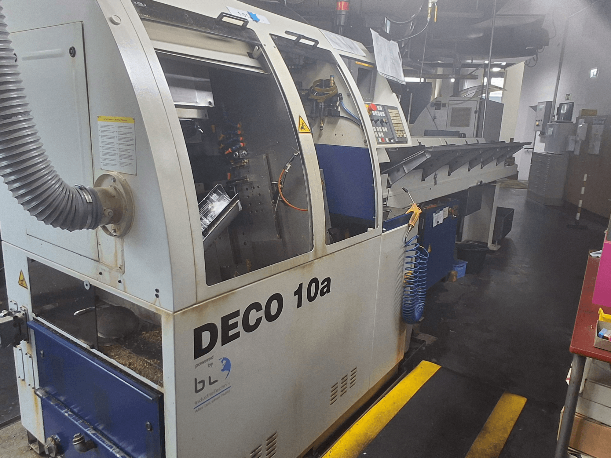 Sveitsiläistyyppinen sorvauskone TORNOS DECO 10a, etukuva; siinä on ohjauspaneeli, näkyvät mekanismit ja pölynpoistoputki.