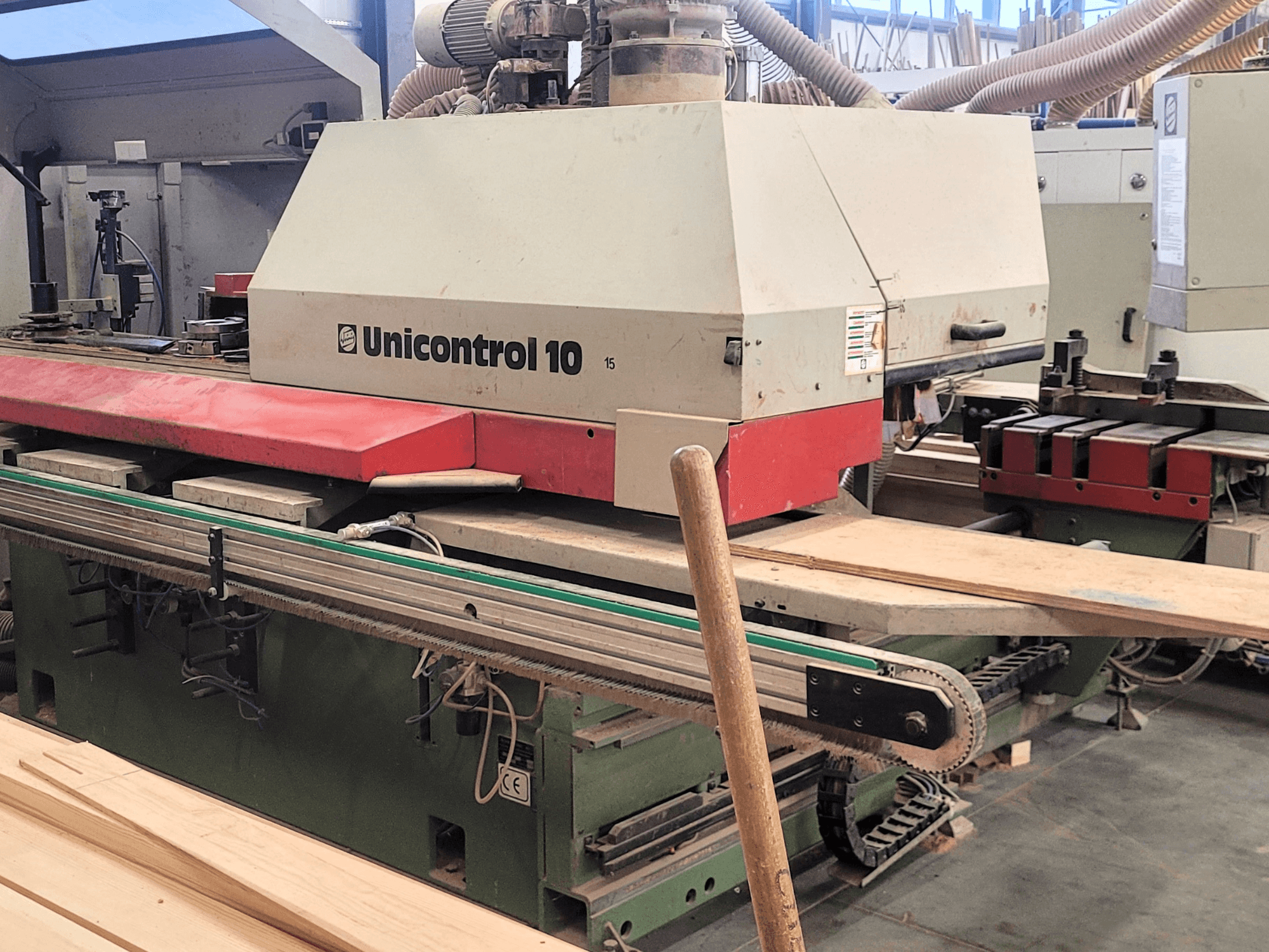 WEINIG/DIMTERin CNC-käsittelykeskus Unicontrol 10, etukuva, jossa on puulevyjä ja laitteita työpajan ympäristössä.