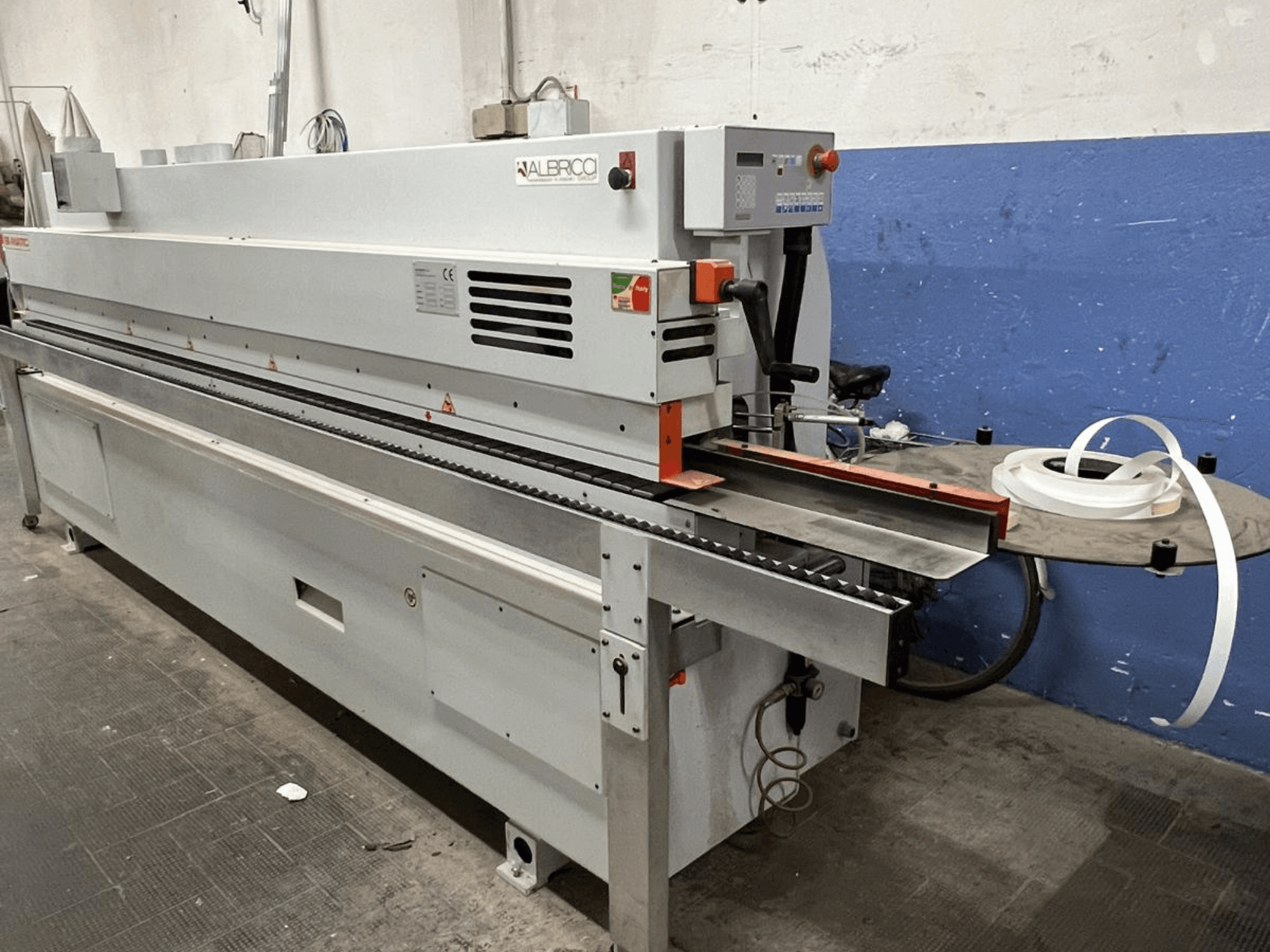 ALBRICO-reunanauhakone etukuvassa, jossa on pitkä kuljetinhihna ja siihen kiinnitetty teippirulla.