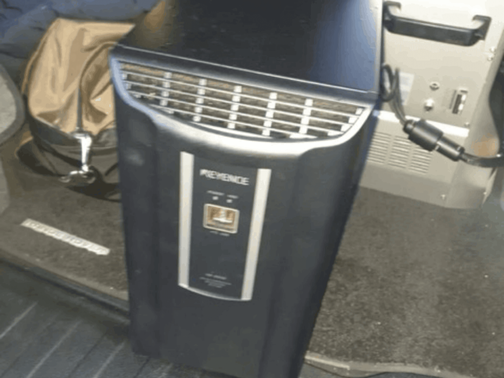 KEYENCE IM-8030 -automaatiojärjestelmä etukuvassa, jossa näkyy ohjauspaneeli ja tuuletusaukot ajoneuvon sisätilojen taustaa vasten.