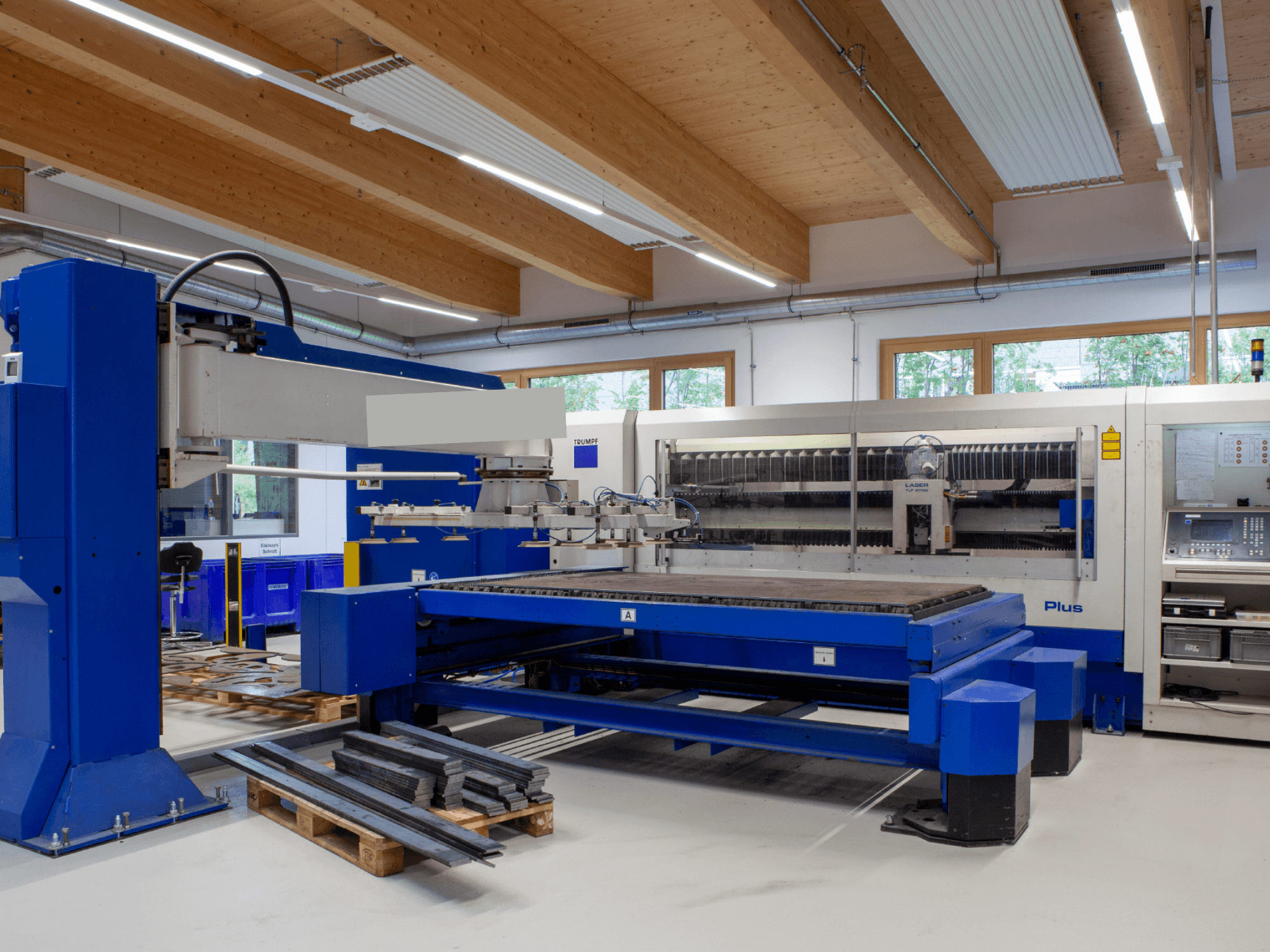 TRUMPF TRUMATIC L 2530 Plus CO₂-laserleikkauskone työpajassa, jossa on esillä suuri leikkausalusta ja teollinen muotoilu.