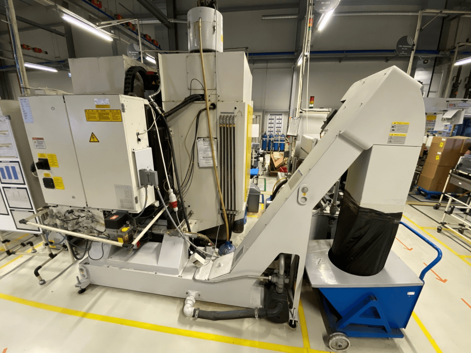 FANUC ROBODRILL α-D21LiB -pystykoneistuskeskus edestä katsottuna; kuvassa näkyvät sähkökomponentit ja poistokouru.