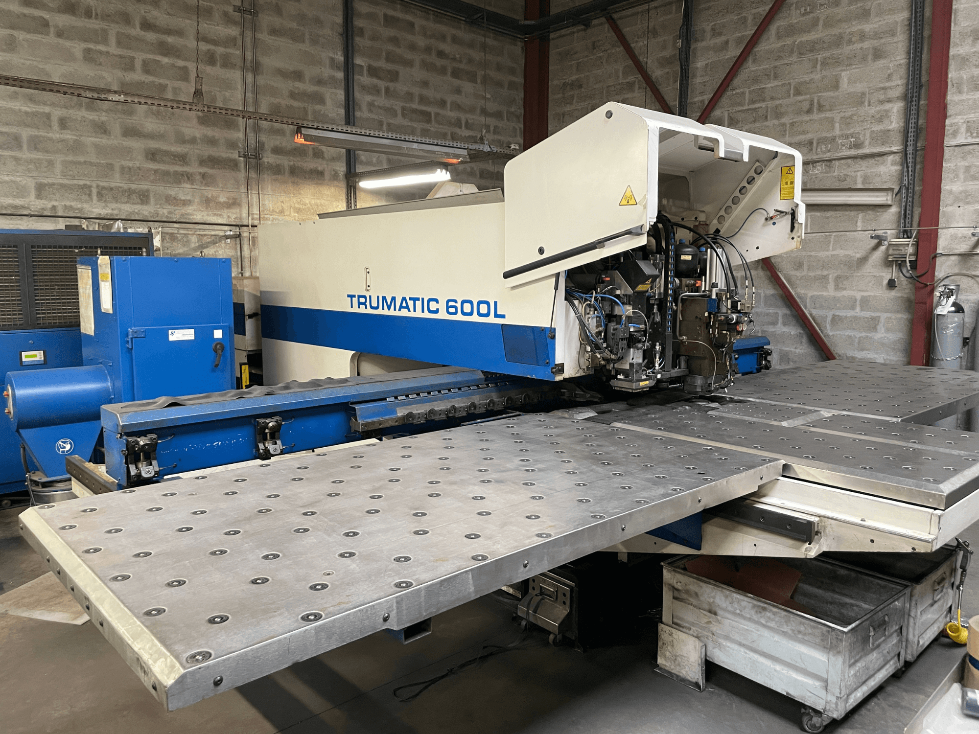 CO2-laserleikkauskone TRUMPF TRUMATIC TC 600L, etukuva, jossa metallileikkauspöytä ja ohjauspaneeli näkyvissä.