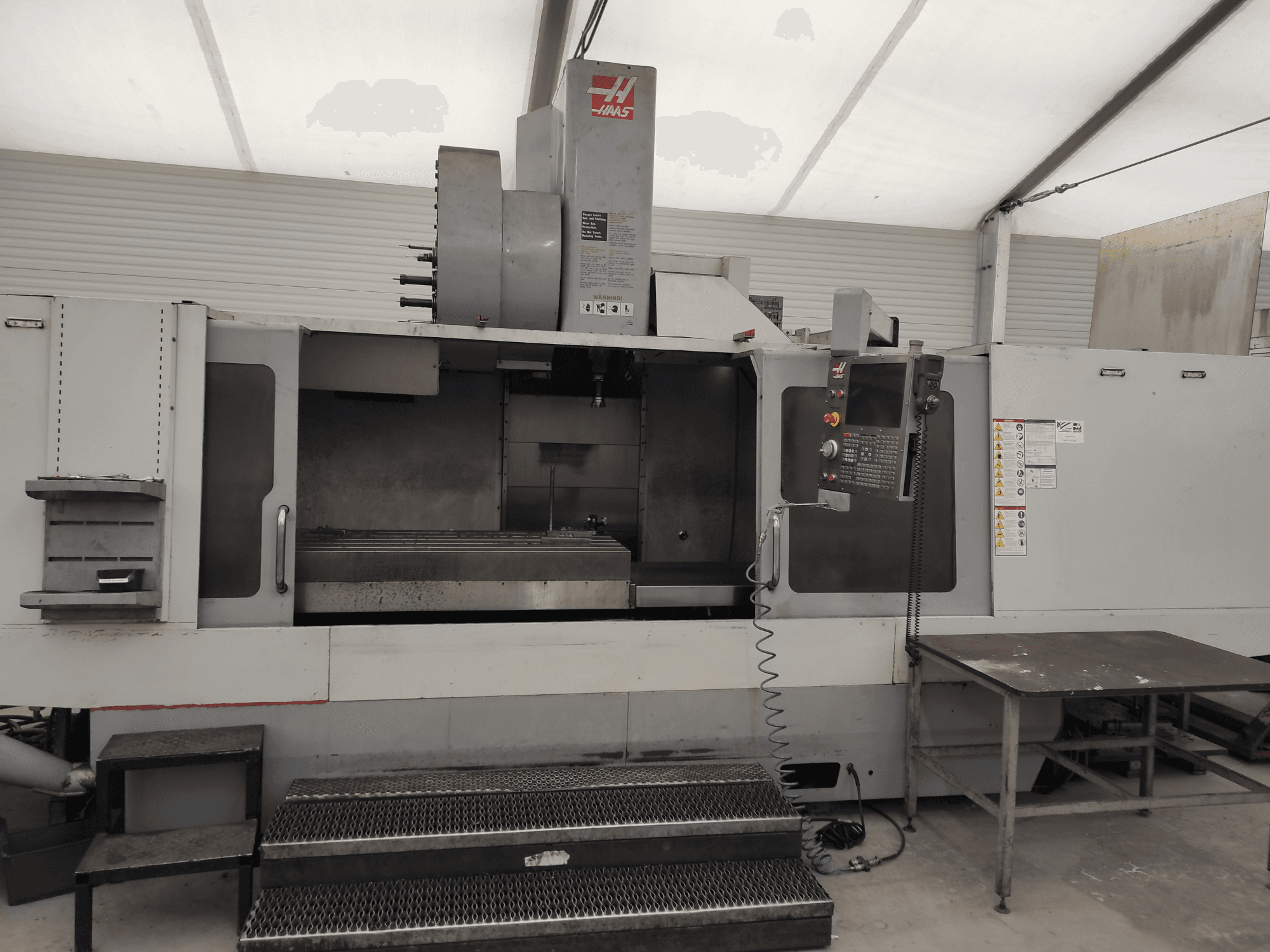 HAAS VF-10/50HE -pystytyöstökeskus, etukuva, jossa näkyy ohjauspaneeli, koneen sänky ja käyttöportaat.