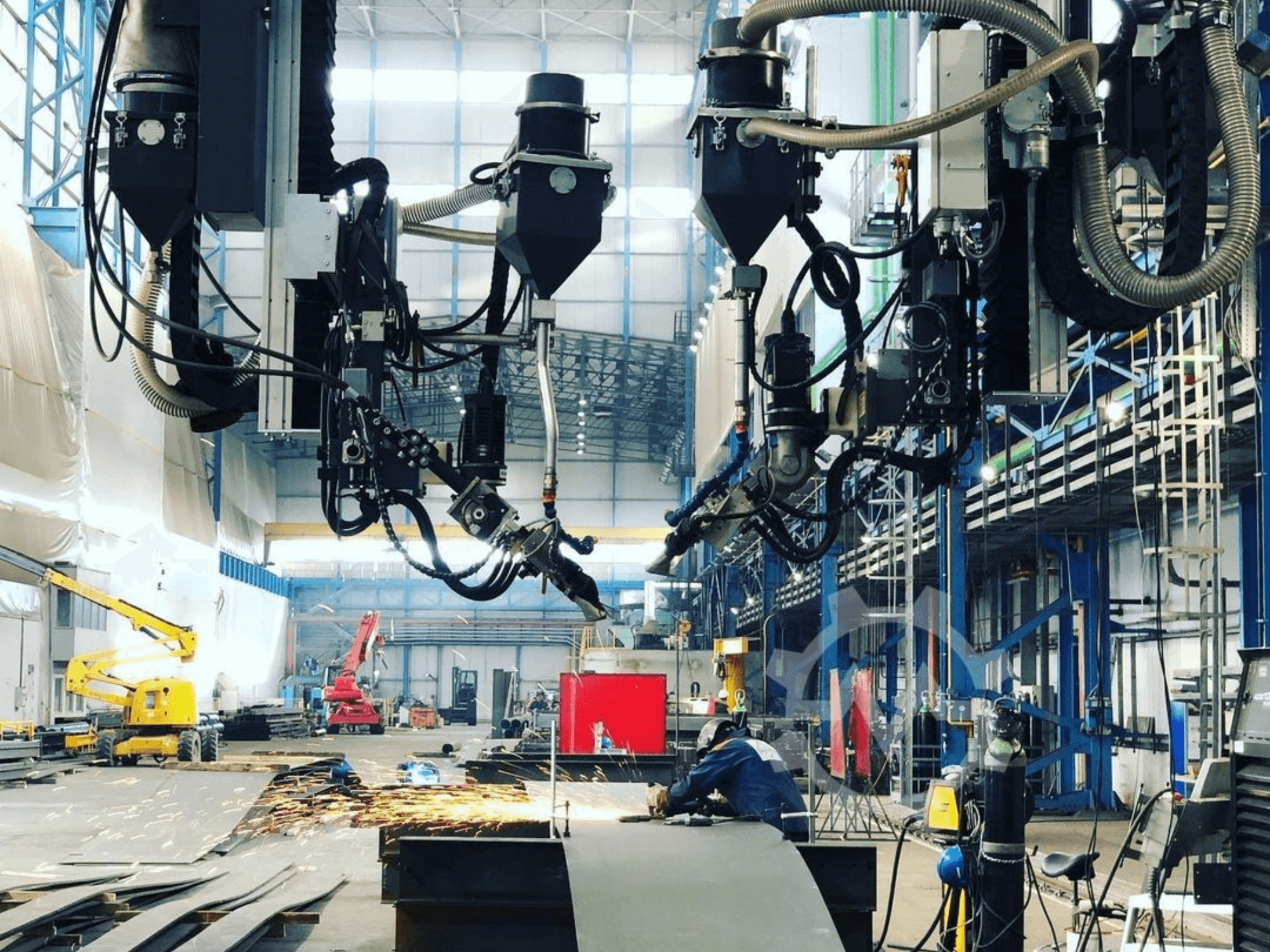 Teollisuusympäristössä oleva robottileikkauskone, jossa kipinöitä lentää, sivulta katsottuna; siinä on useita lisälaitteita ja letkuja.