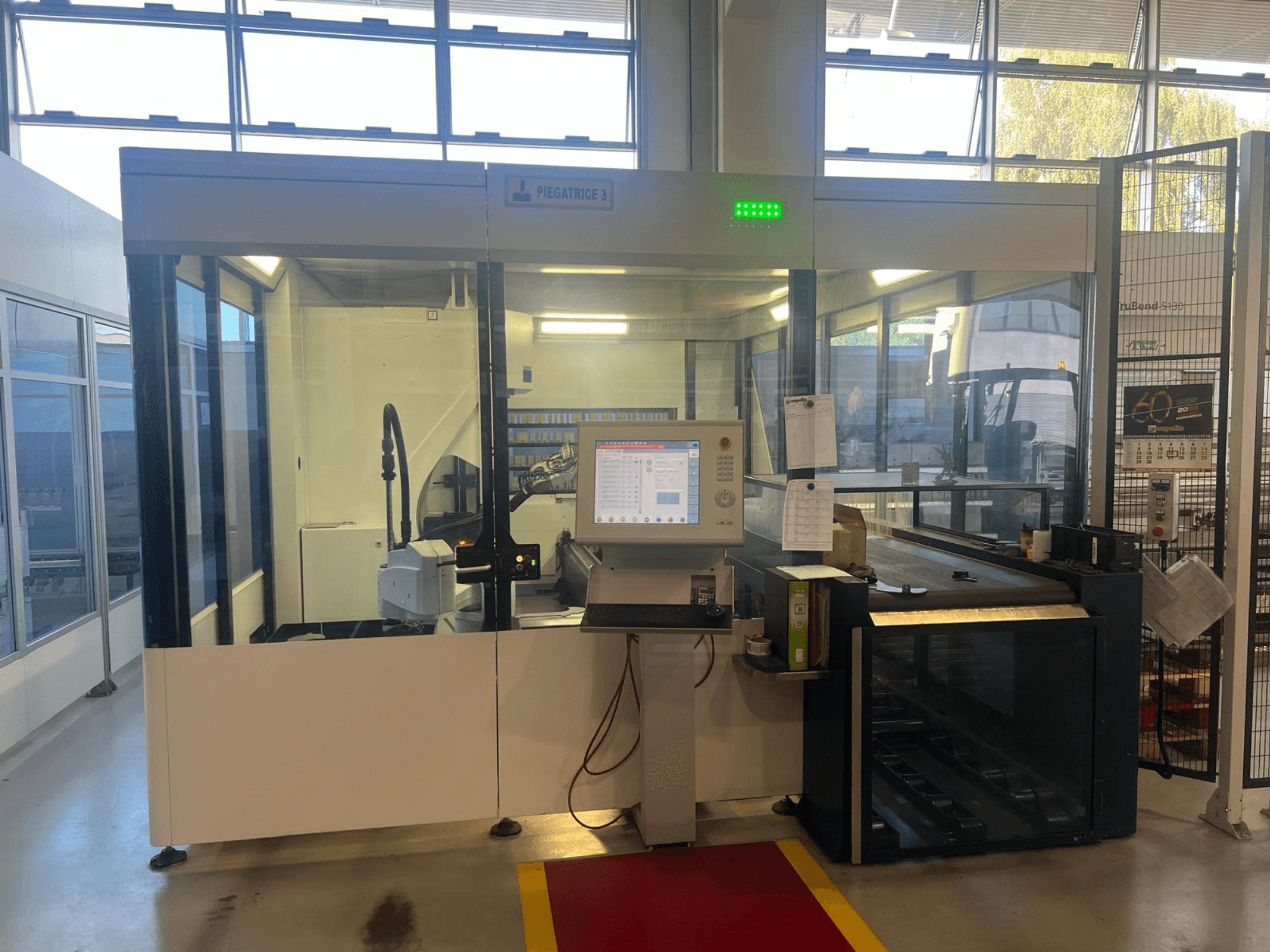 Teollinen taivutuskone, malli Piegatrice 3, etukuva, jossa on ohjauspaneeli ja robottivarsi, hyvin valaistussa työpajassa.