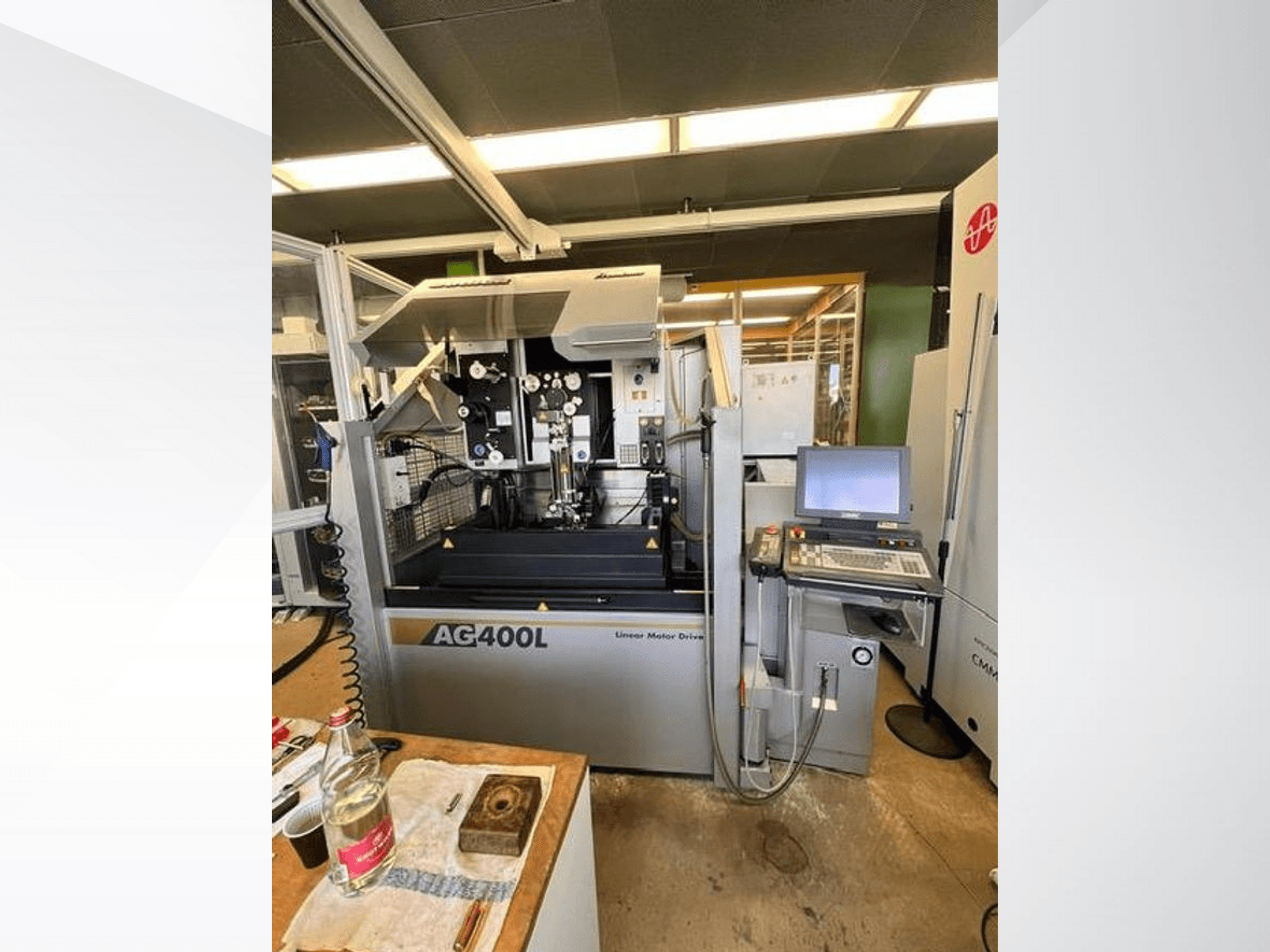 AG400L lineaarimoottorikäyttöinen kone, etukuva, jossa on ohjauspaneeli ja työskentelyalue, jossa on näkyvissä turvatoimintoja.