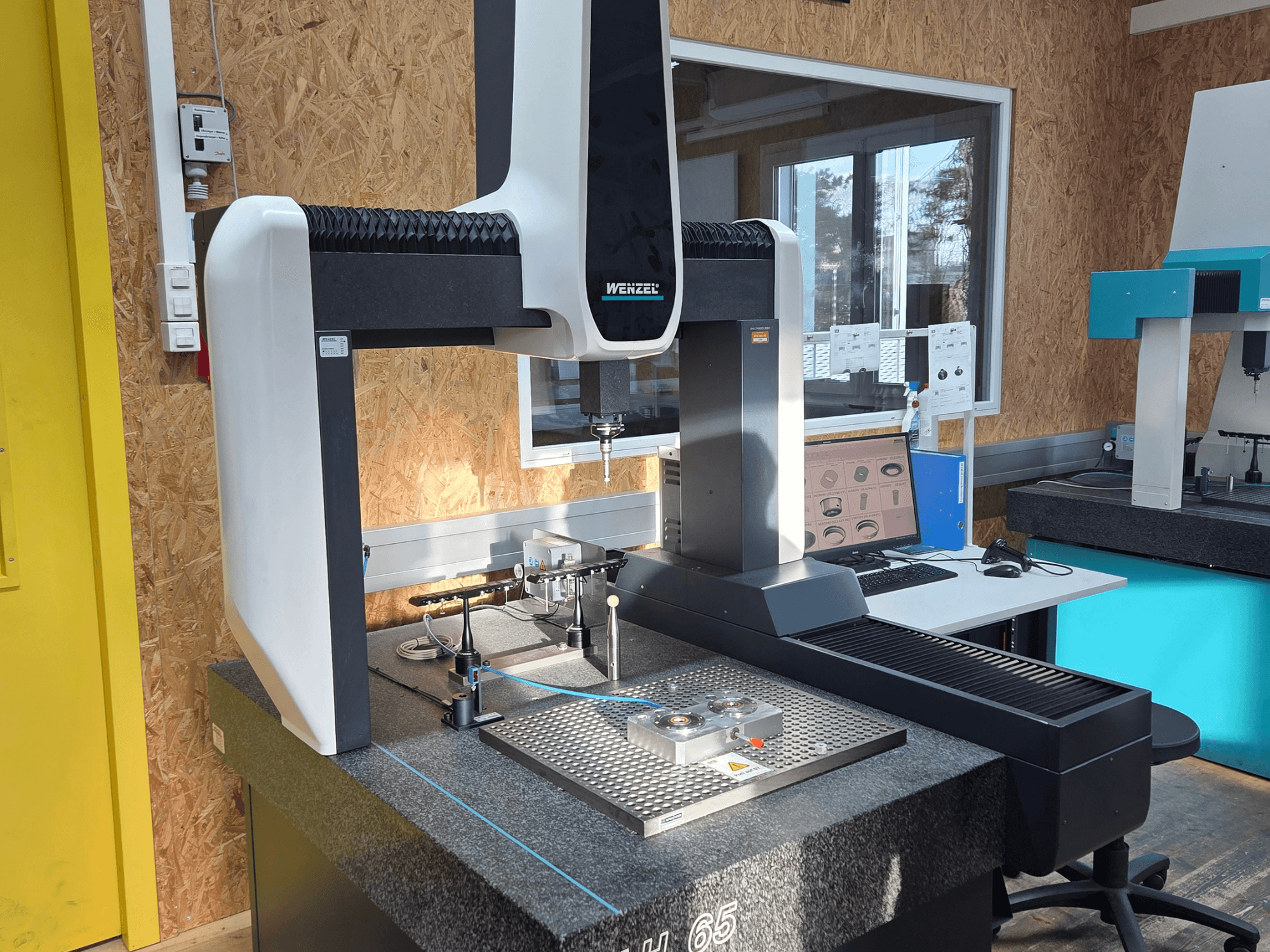 Wenzel LH 65 -koordinaattimittauskone laboratorioasennuksessa, etukuva, jossa on mittaustyökalut ja näyttö.