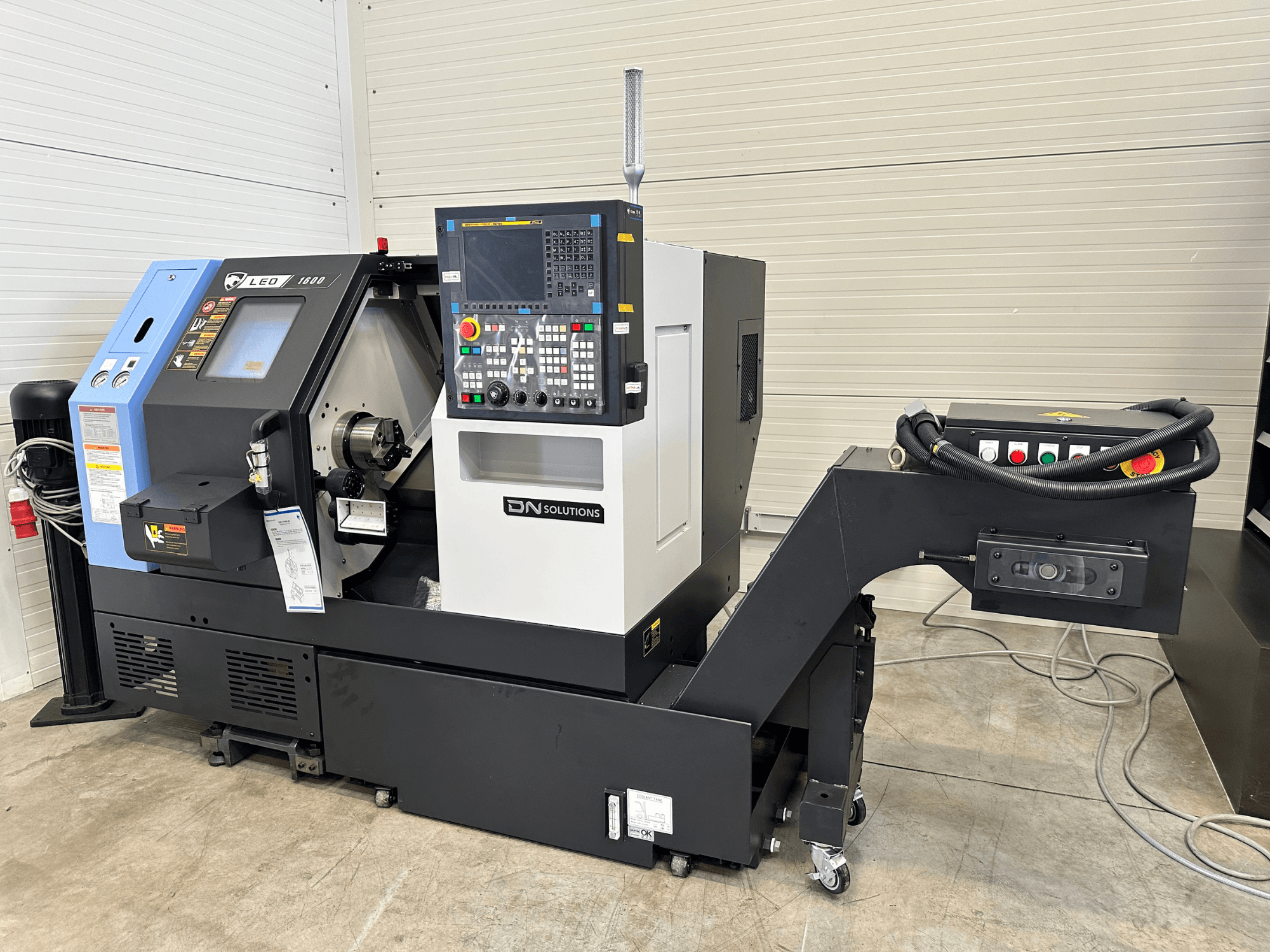 Etukuva DN SOLUTIONS Leo 1600 -jyrsinkeskuksesta, jossa on digitaalinen ohjauspaneeli ja työkalunpidin mustalla alustalla.