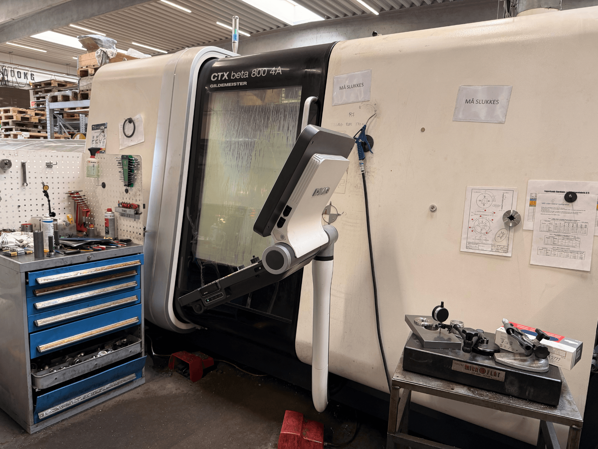 DMG MORI CTX Beta 800 4a -pystysorvauskone työpajassa, ohjausvarsi ja tekniset asiakirjat lähellä.