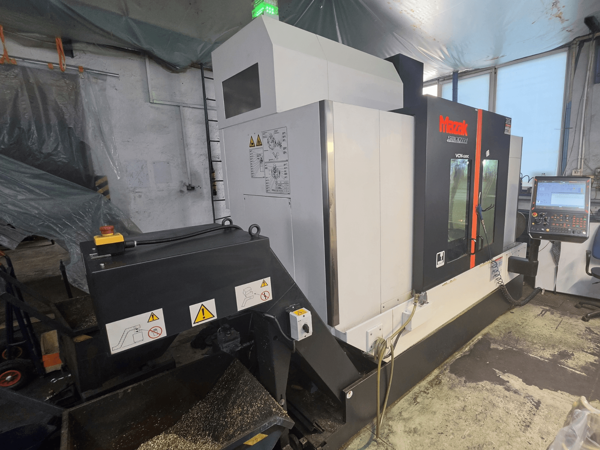 Mazak VCN-530C -pystykoneistuskeskus edestä katsottuna; kuvassa näkyvät ohjauspaneeli, työkaluketju ja toimintamerkit.