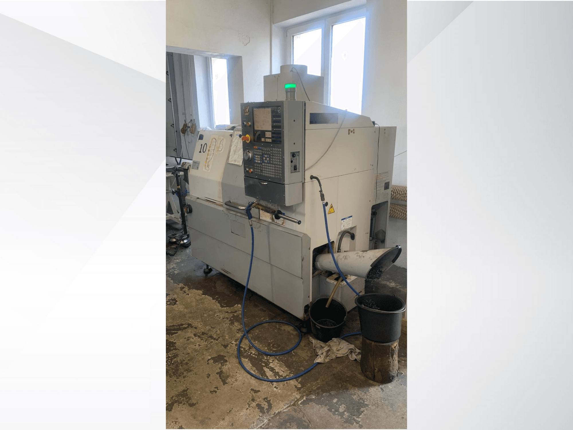 Haas CNC-koneen malli, jossa on ohjauspaneeli, sivukuva, jossa on jäähdytysnesteen johto, jätekouru ja alla olevat säilytysastiat.