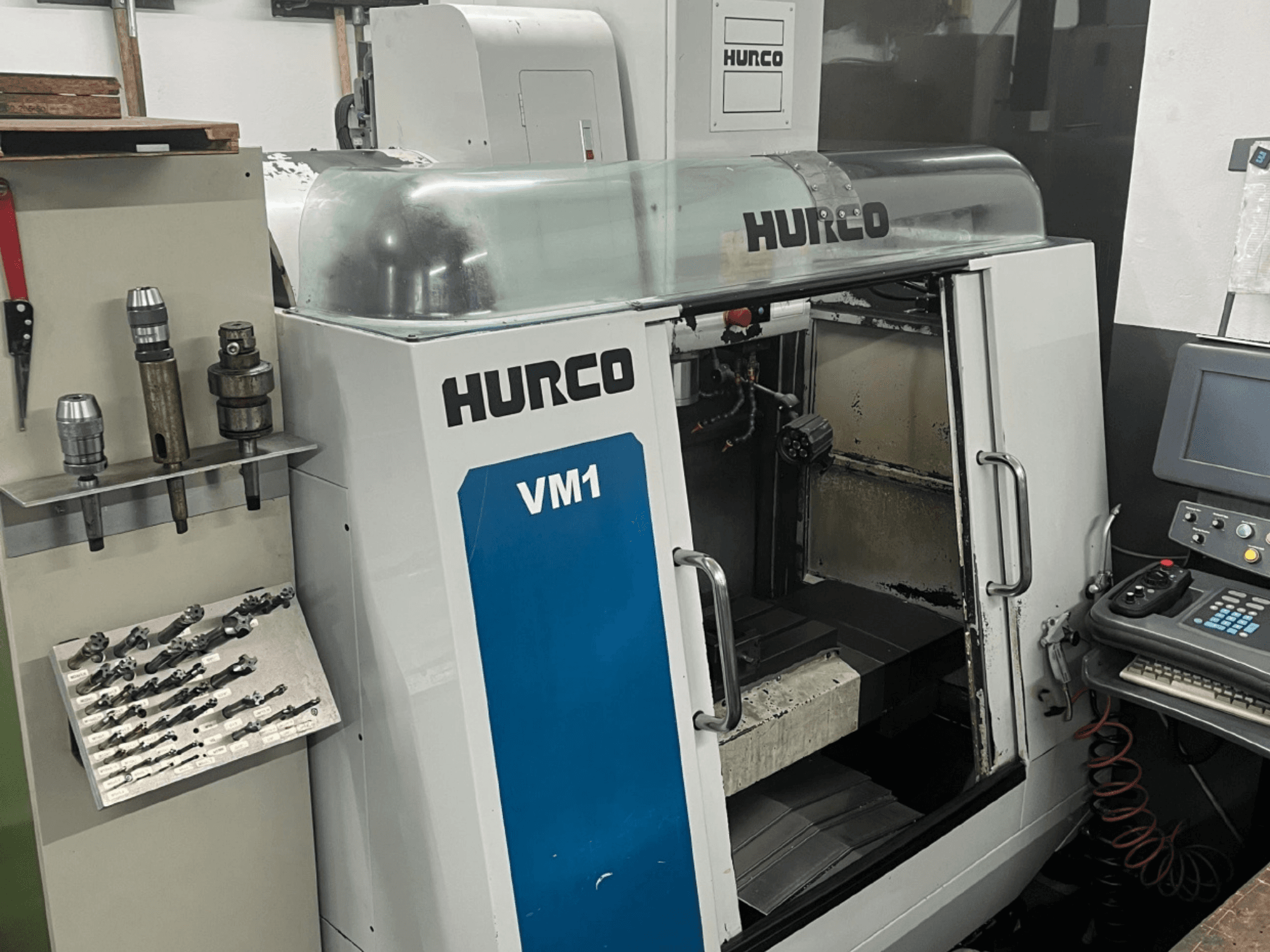 Hurco VM1 -pystytyöstökeskuksen etukuva, jossa on läpinäkyvä kansi, ohjauspaneeli ja asennetut työkalut.