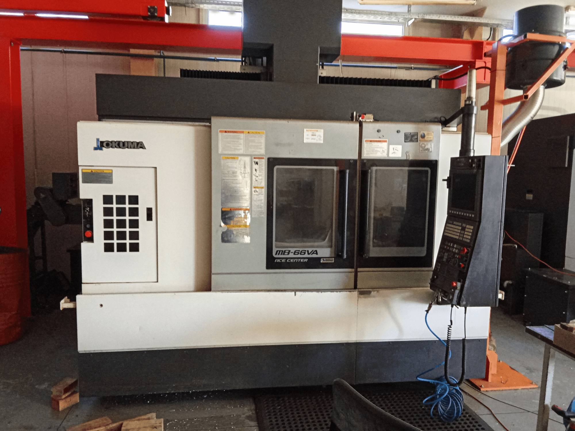 Okuma MB-66VA -pystytyöstökeskus, etukuva, jossa näkyy ohjauspaneeli ja kaksi ikkunaa työkalujen käyttöä varten.