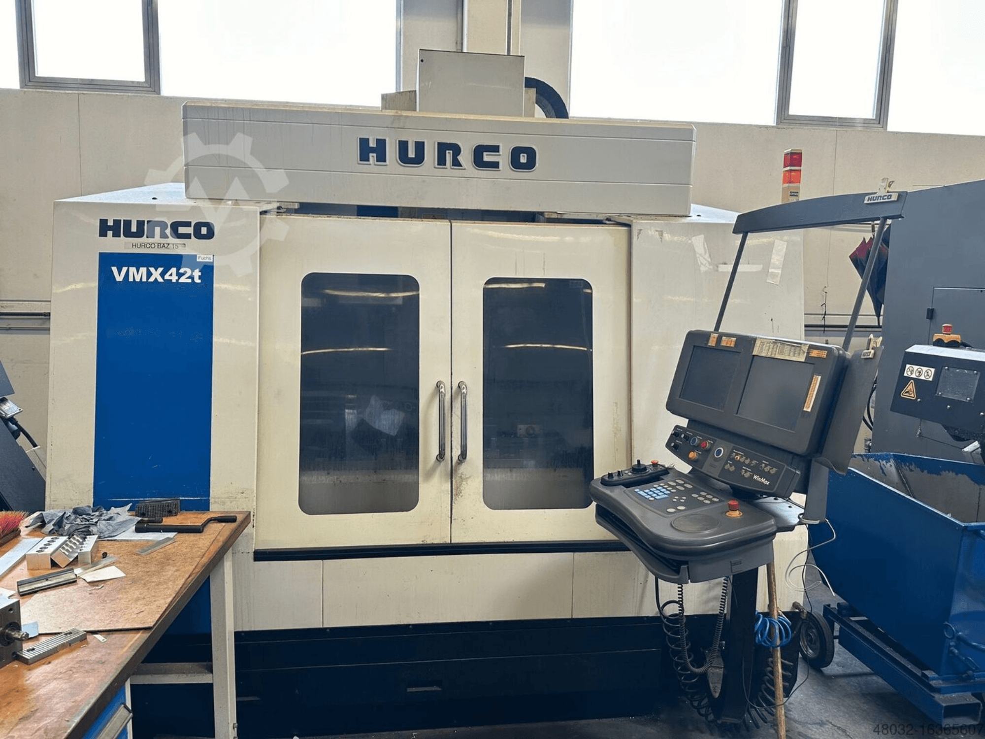 Hurco VMX42t -pystykoneistuskeskuksen etunäkymä, jossa näkyvät ohjauspaneeli ja koneen sisätilat, joissa on työkaluja ja työkappaleita.