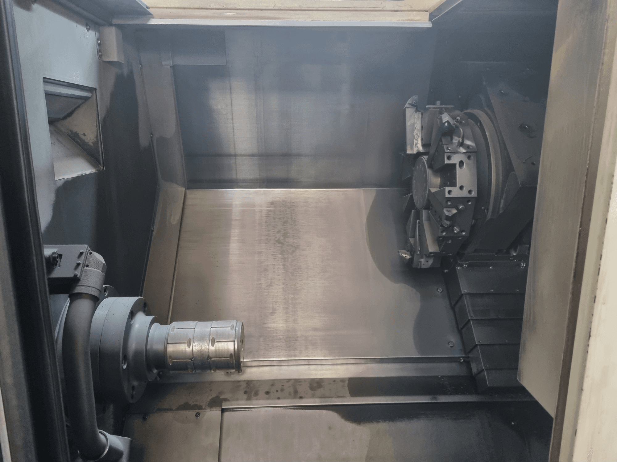 CNC-koneen sisäkuva, jossa näkyy metallityöalue, työkalunpidin ja ruuvipuristin; korostaa tarkkuutta.