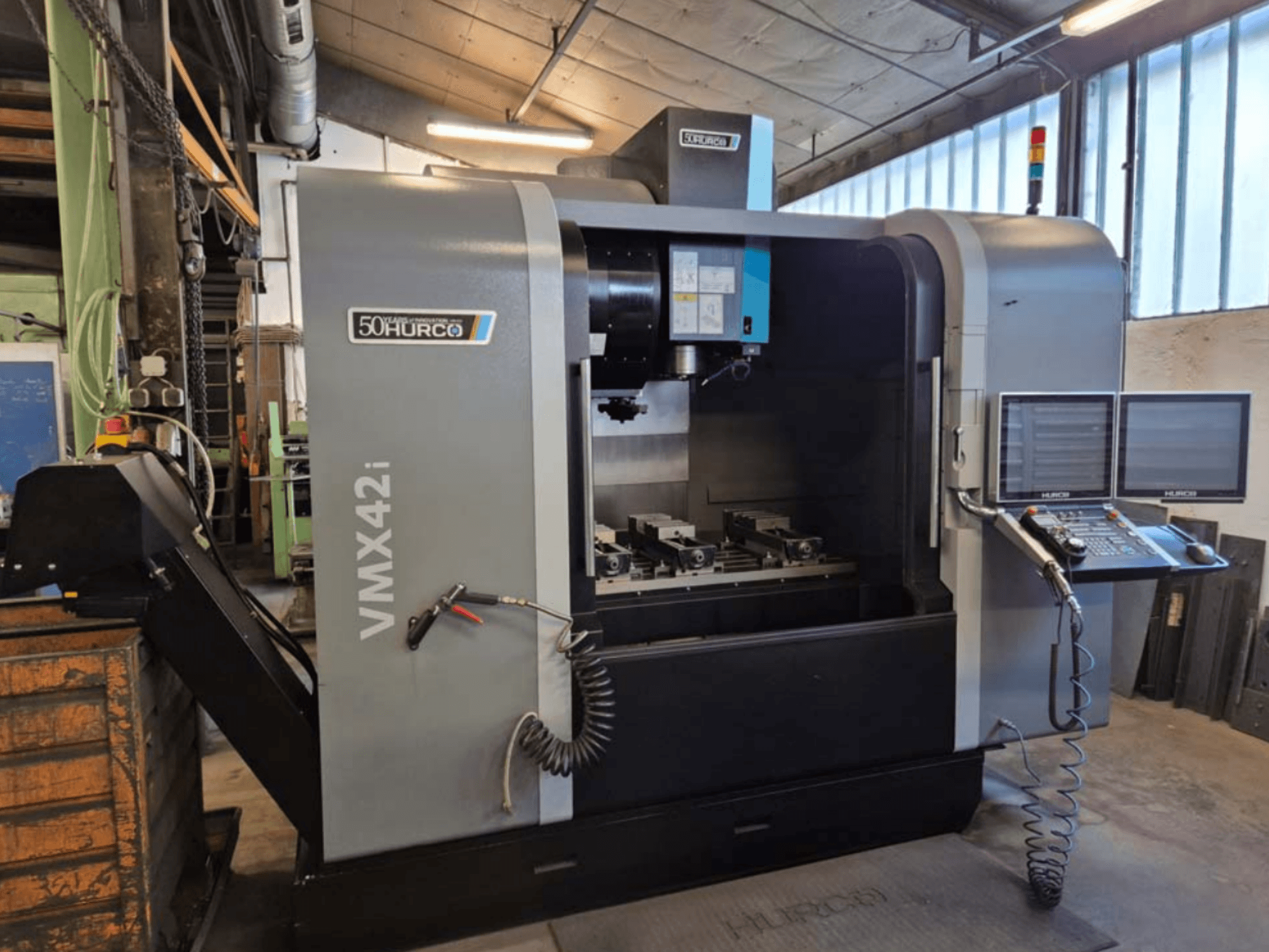 Hurco VMX 42i -pystytyöstökeskus, etukuva, jossa näkyy ohjauspaneeli ja työalue ruuveineen.