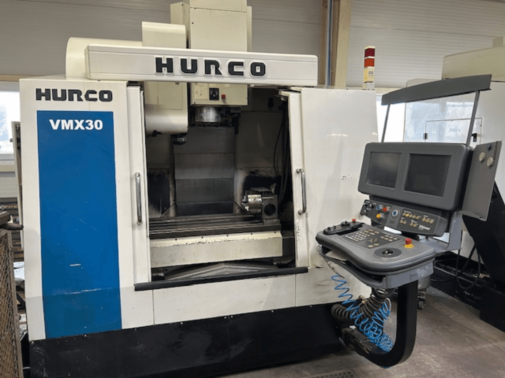 Hurco VMX30 CNC-jyrsinkone työpajassa, etukuva; ohjauspaneelissa on kaksi näyttöä ja käyttöpainikkeet.