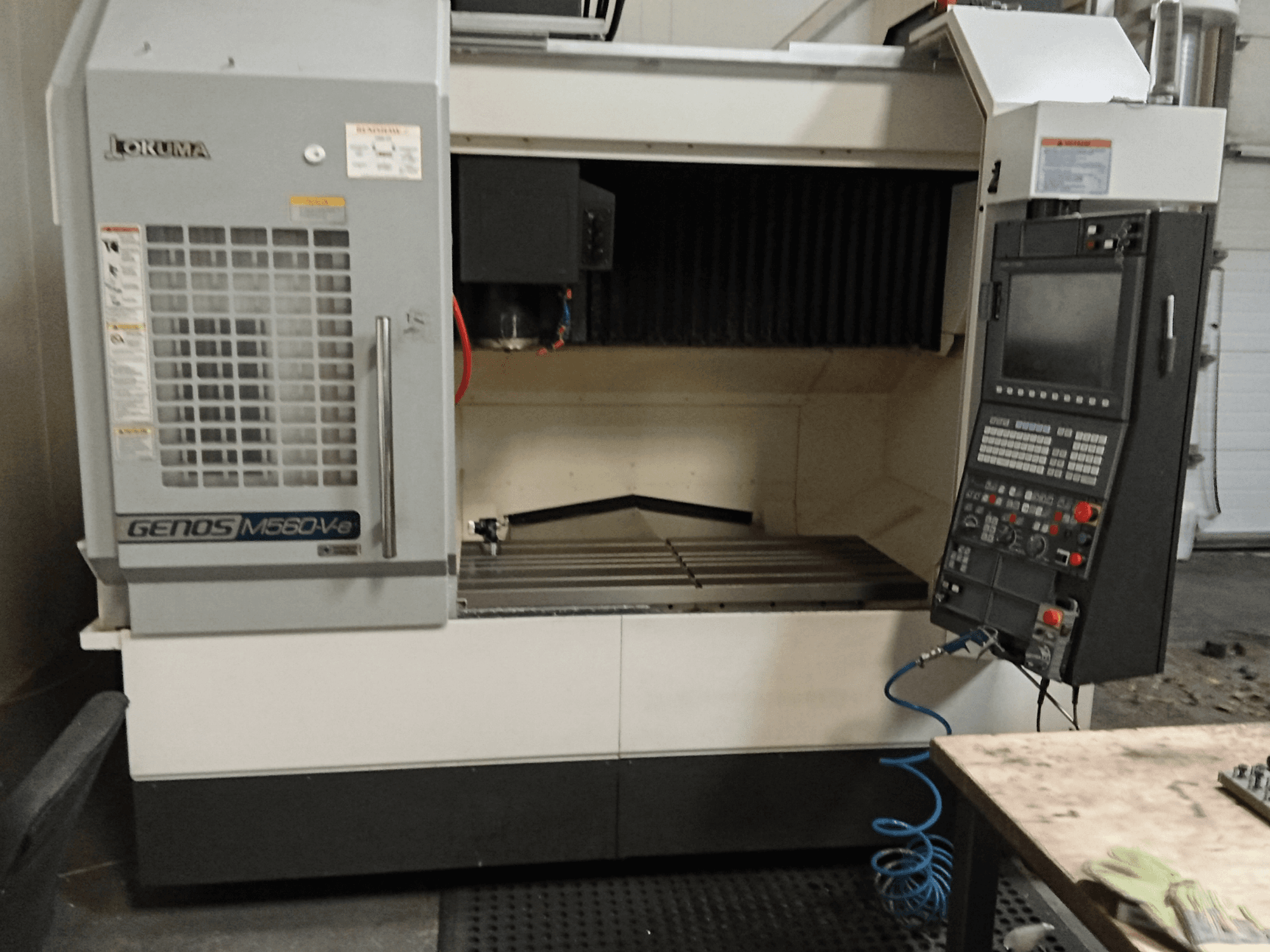 Okuma GENOS M560-V, etukuva pystysuorasta työstökeskuksesta, jossa on ohjauspaneeli, CNC-käyttöliittymä ja näkyvä leikkausalue.
