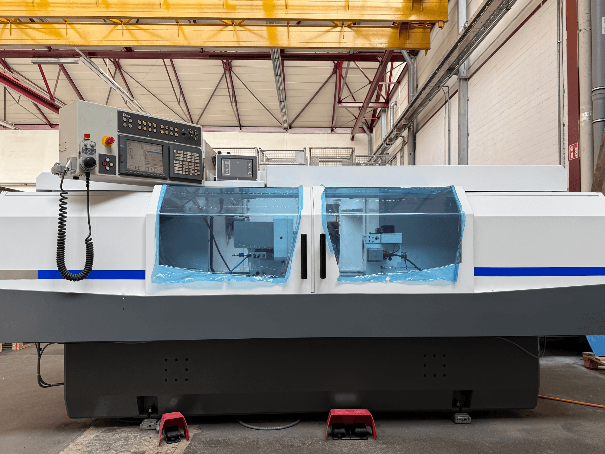STUDER S33 CNC -sylinterihiomakone sivulta katsottuna, ohjauspaneeli ja läpinäkyvät suojakannet näkyvissä.