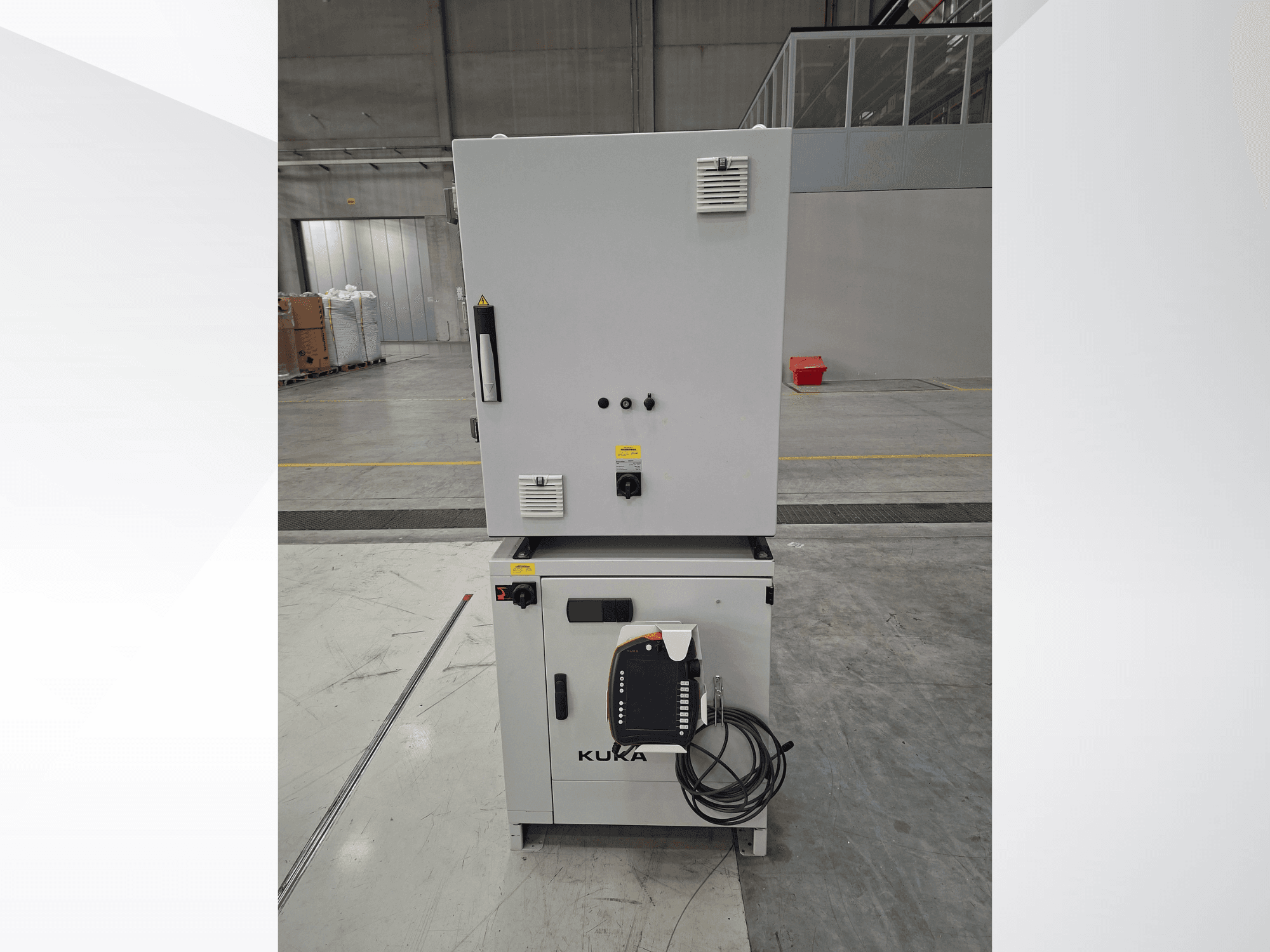 KUKA KR 90 R2700 PRO C4 FLR -robottivarren ohjainlaite, etunäkymä, jossa näkyvät ohjauspaneeli ja turvallisuusmerkinnät tilavassa varastossa.