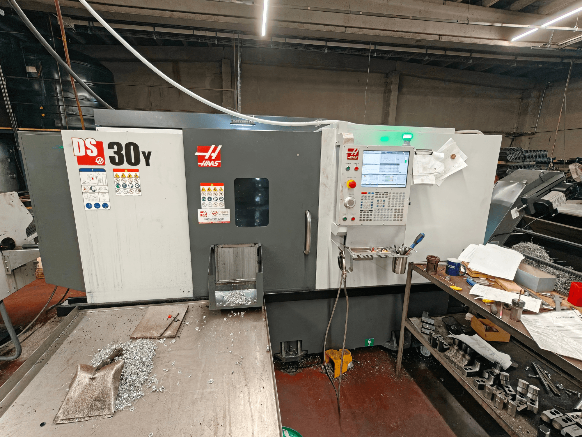 HAAS DS30Y -vaakasuora sorvi työpajassa, etunäkymä, jossa näkyy ohjauspaneeli ja pinnalla olevat metallilastut.
