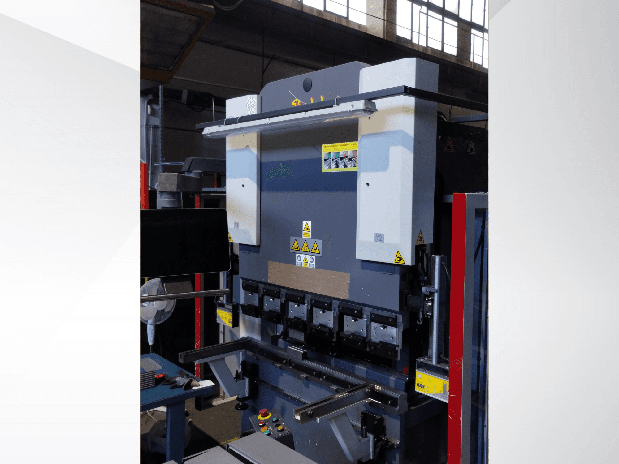 Puristusjarrukone, etukuva. Siinä on näkyvät hallintalaitteet, turvatarrat ja useita muotinpidikkeitä tarkkaa taivutusta varten.