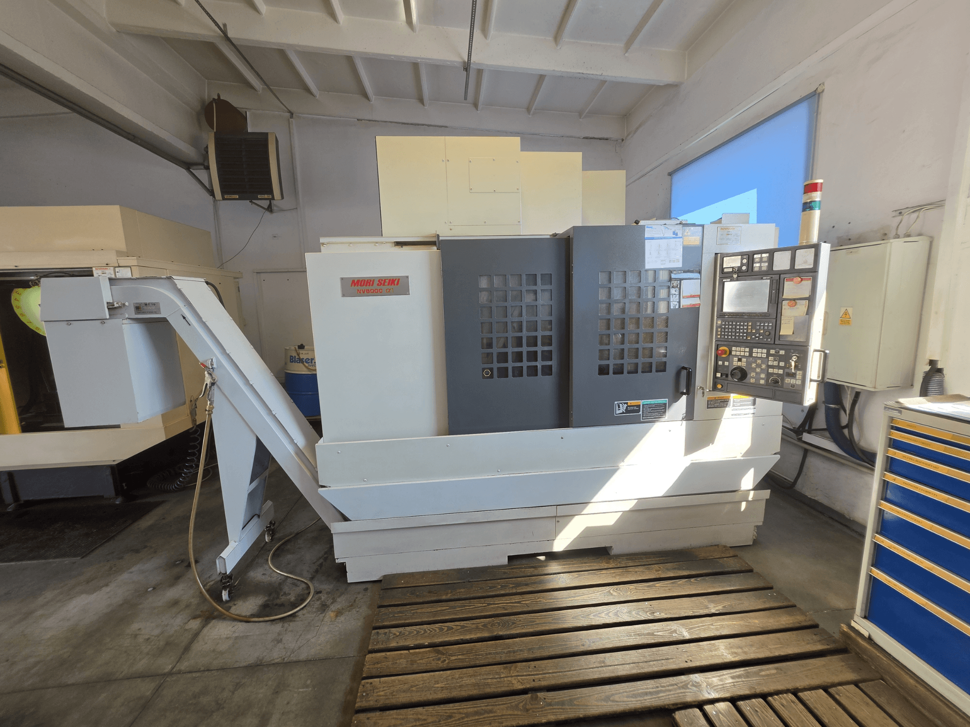 MORI SEIKI NV 5000 alpha1 -pystykoneistuskeskus, etunäkymä, jossa näkyvät ohjauspaneeli ja koneen ominaisuudet työpajaympäristössä.
