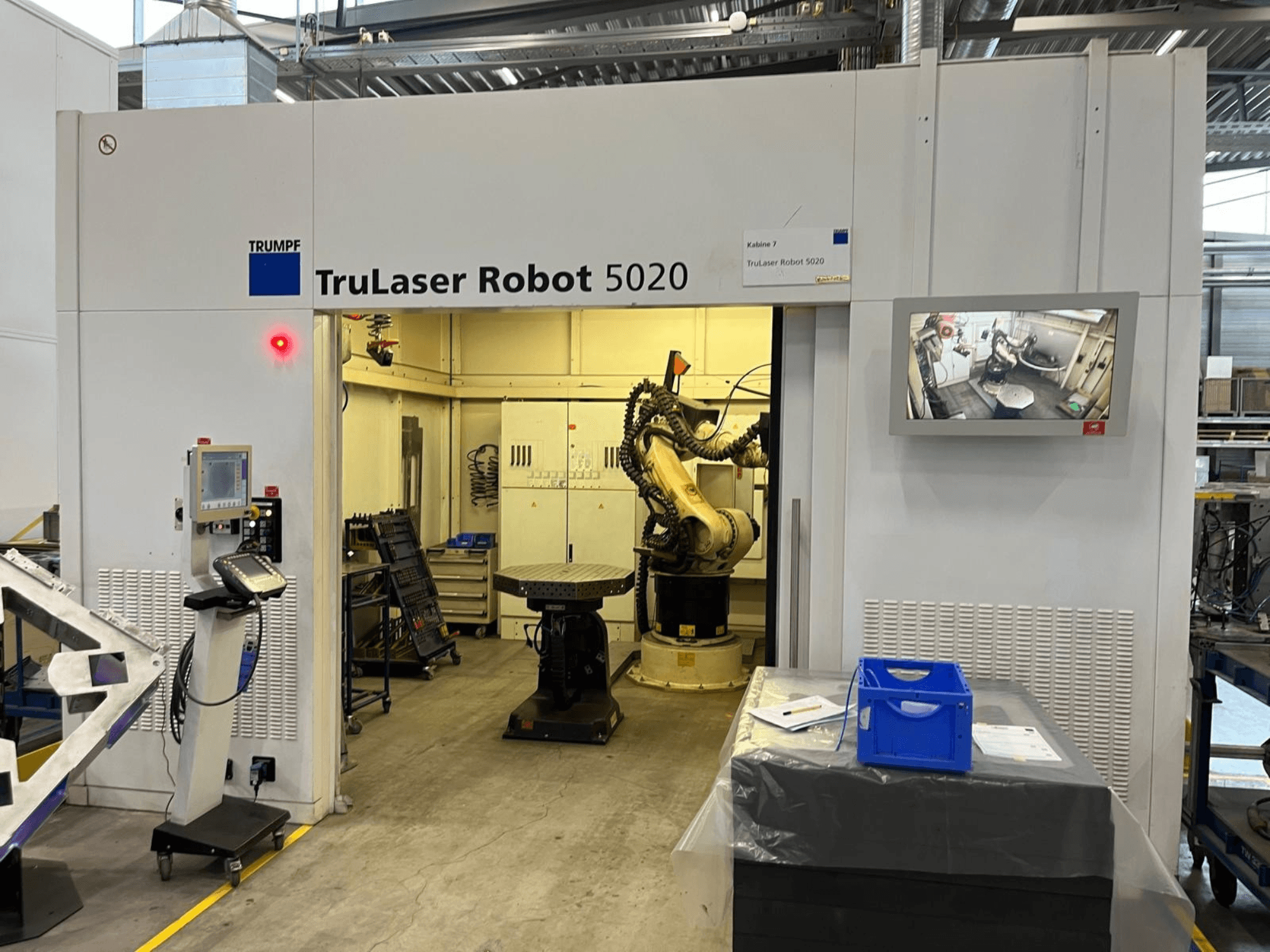 TRUMPF TruLaser Robot 5020 teollisuusympäristössä, jossa näkyvät ohjauspaneeli, robottivarsi ja toimintoja näyttävä näyttö.
