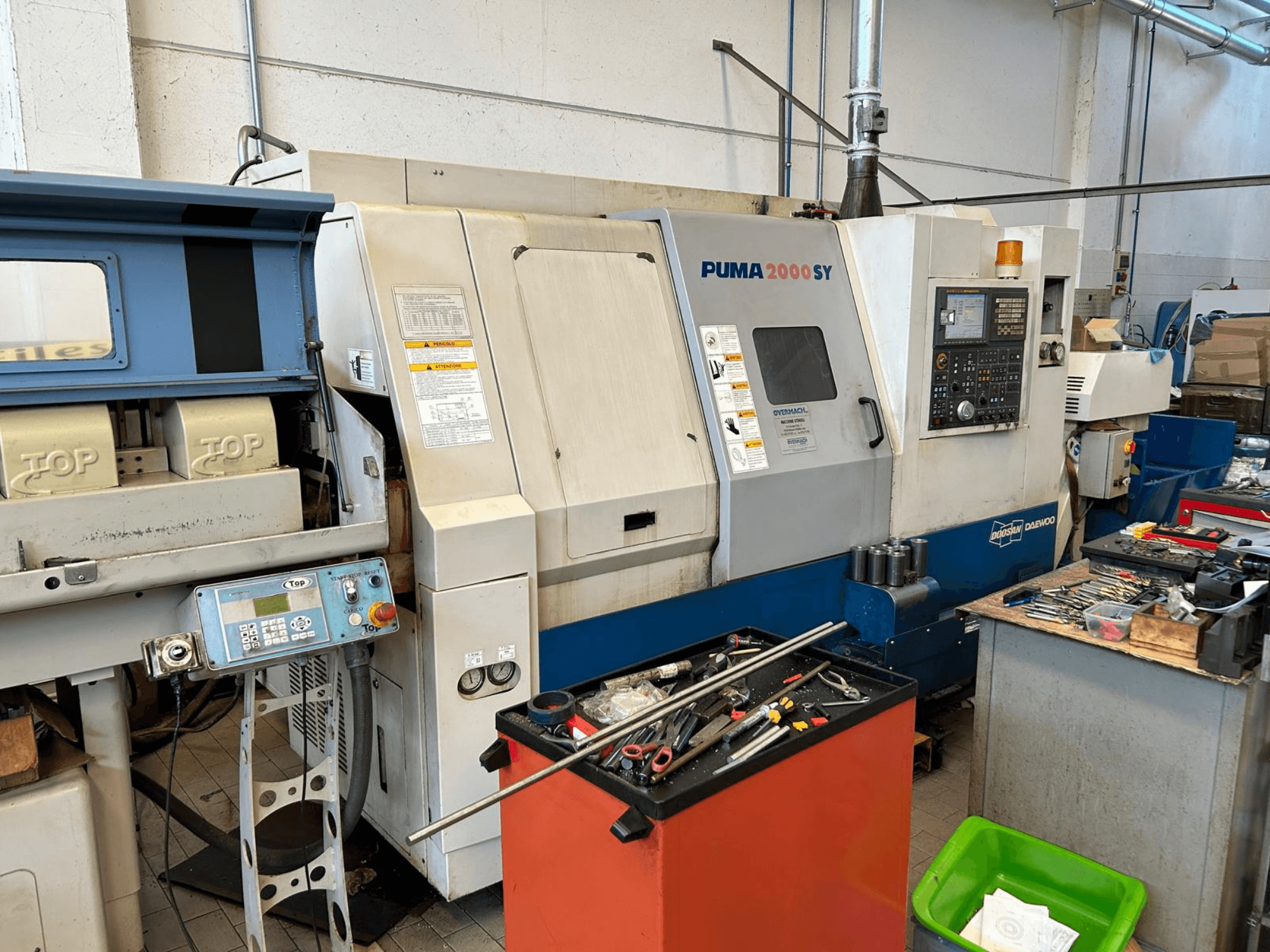 DOOSAN PUMA 2000SY -vaakasuora sorvi työpajassa; sivukuva, jossa näkyvät ohjauspaneeli ja sen vieressä olevat työkalut.